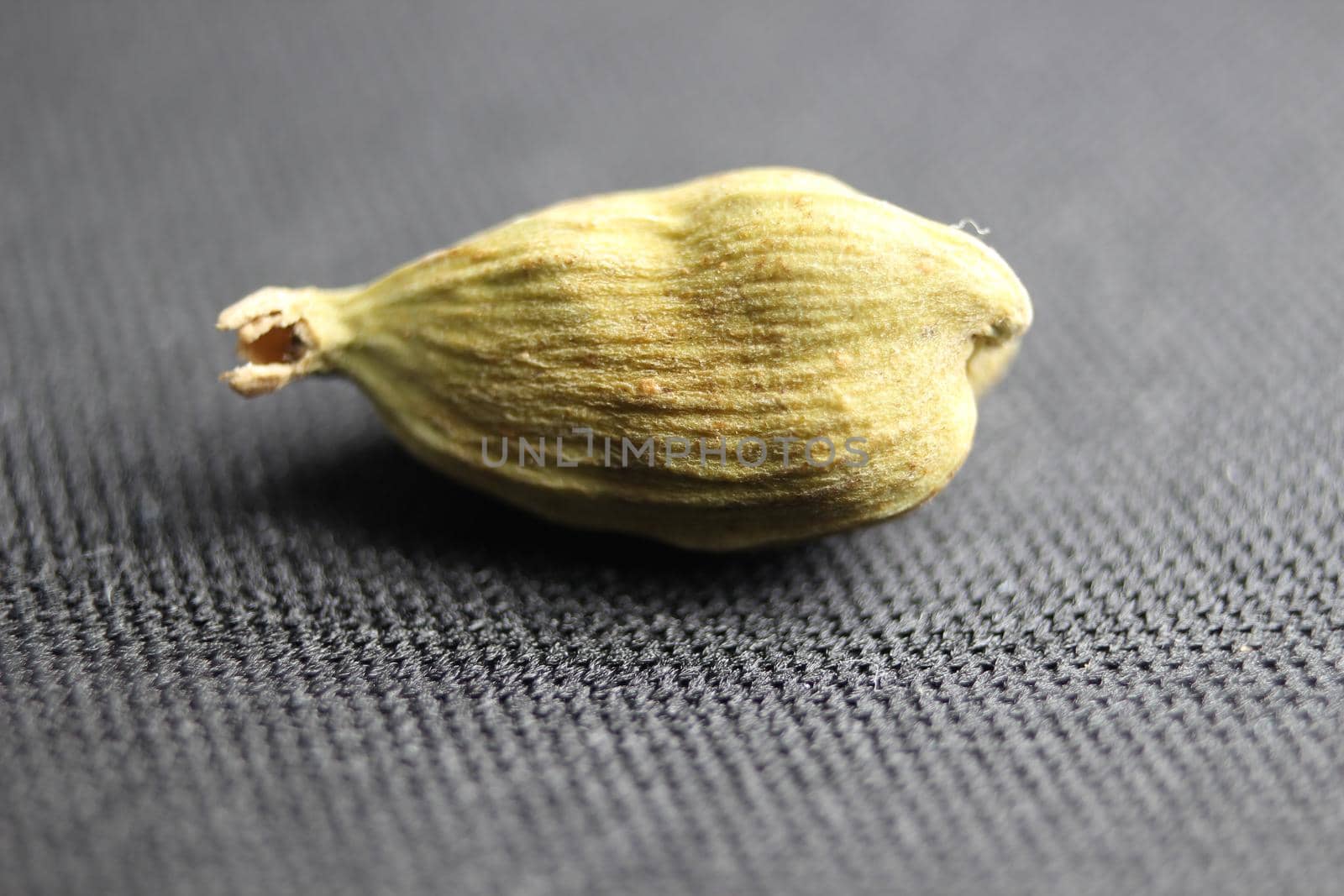 Closeup top view of dried green Elettaria cardamomum fruits with seeds, cardamom spice scattered on white background