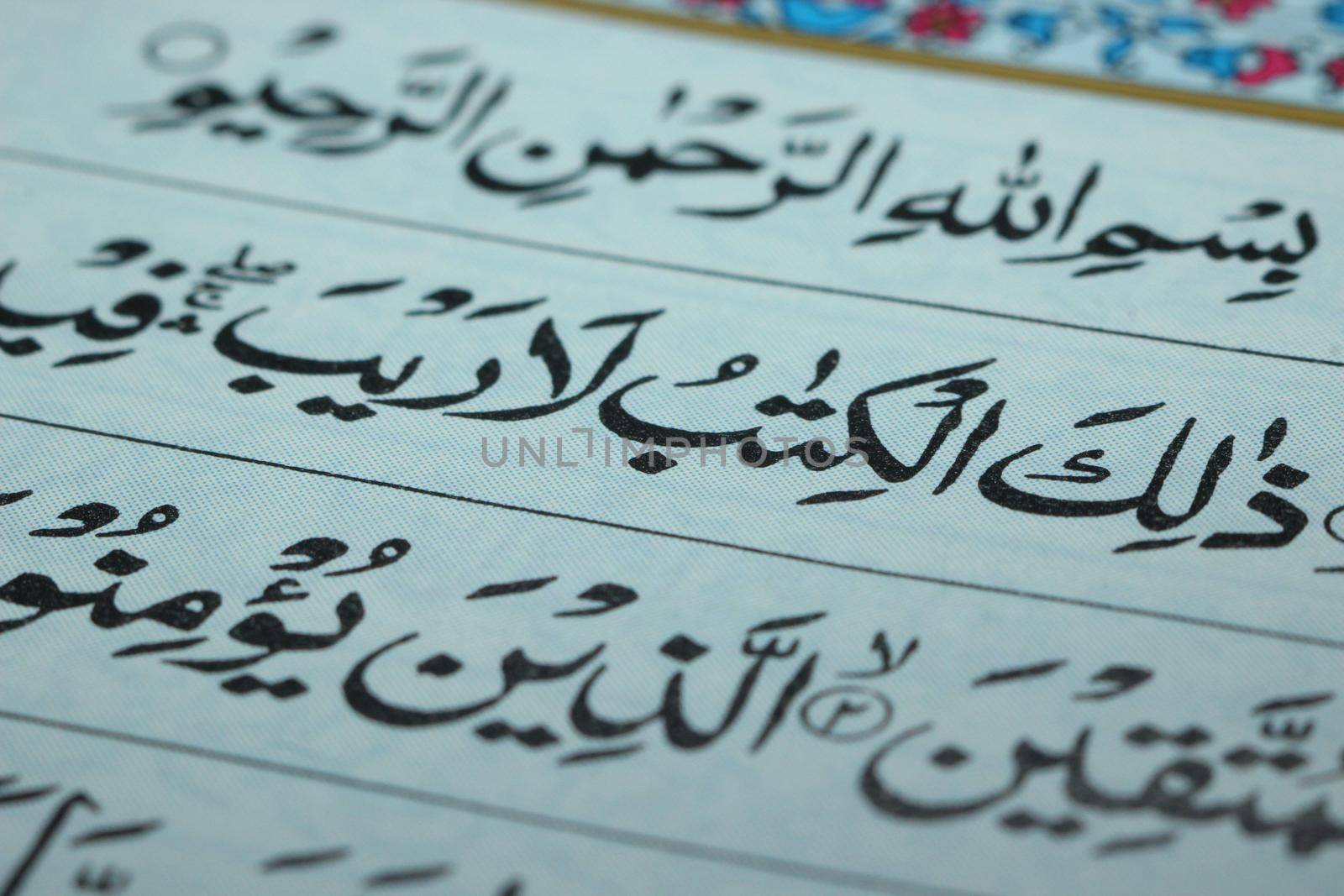 Closeup shot of Islamic Book Quran with golden arabic calligraphy by Photochowk