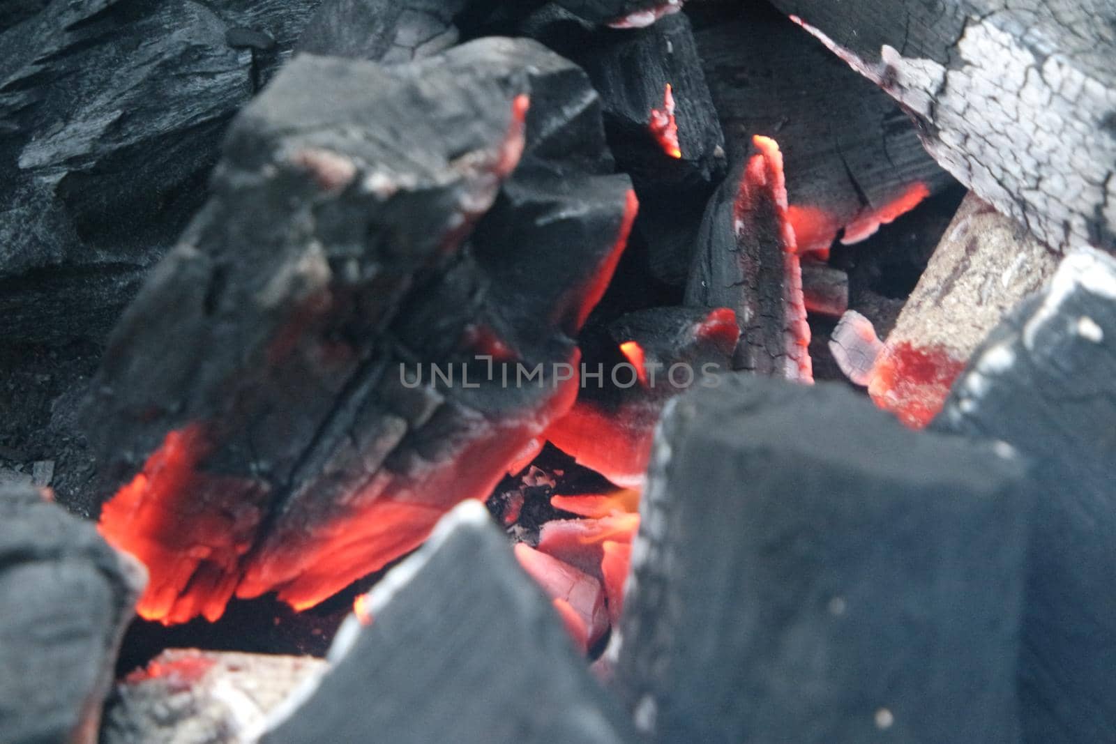 Fire on logs in fire pot with embers and burning coal and blazing flames. by Photochowk