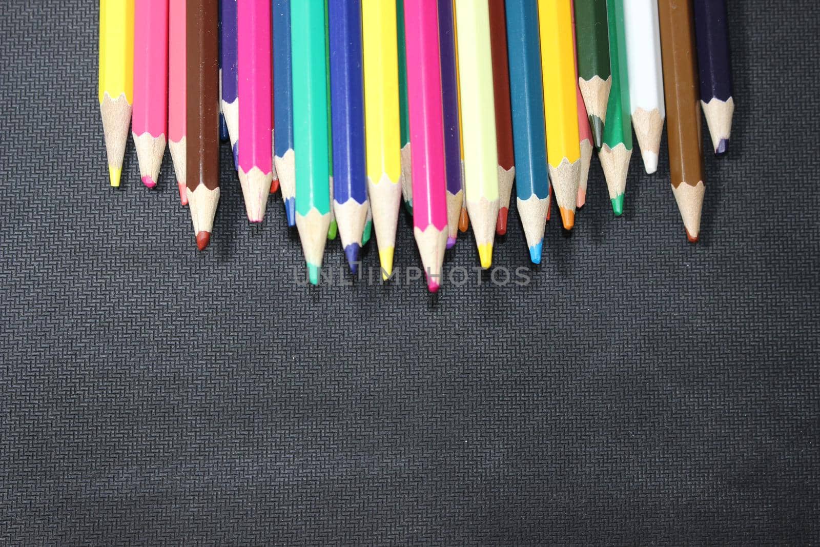 Close-up view of bright colored multicolor pencils on black background