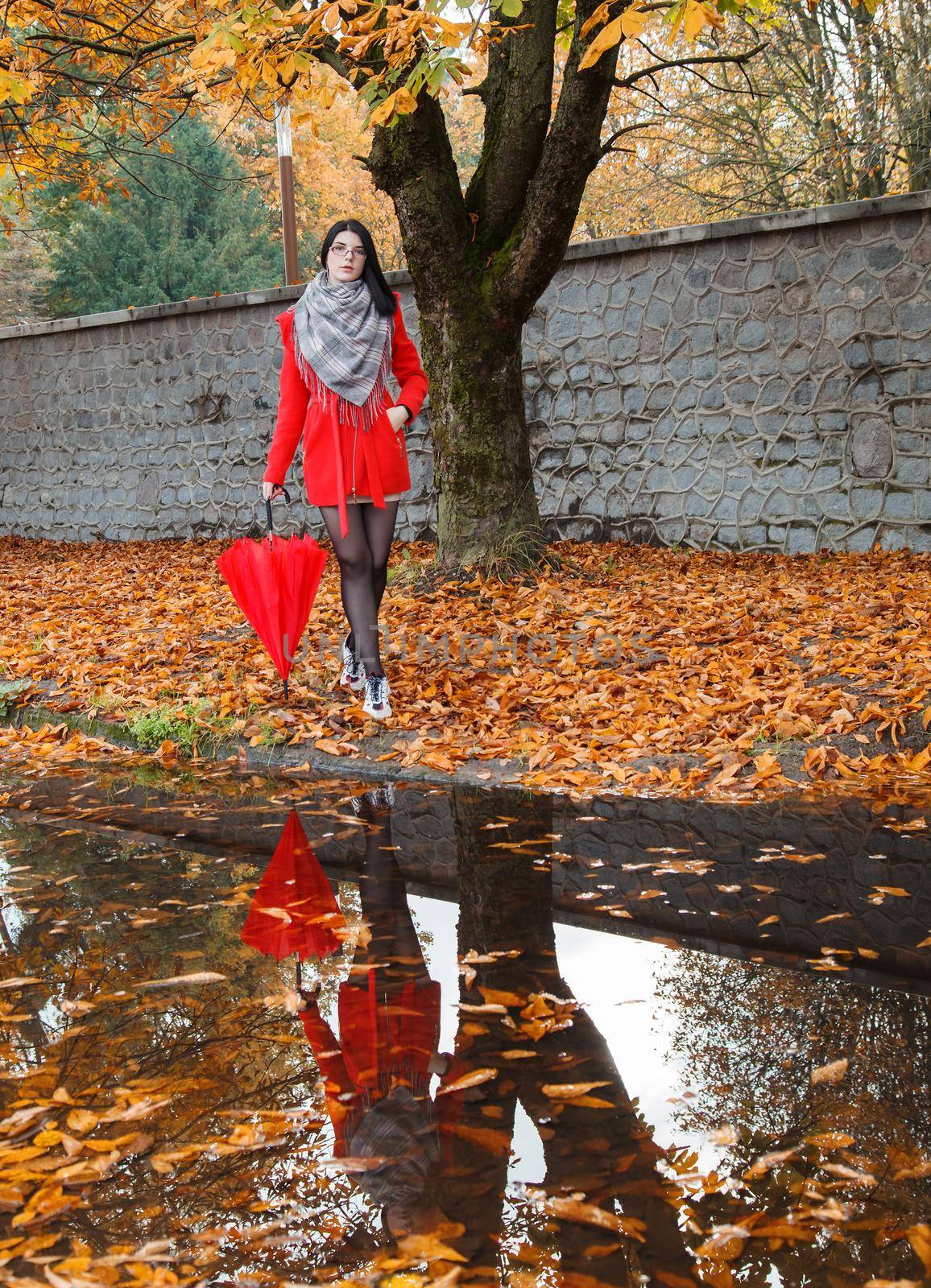 young girl with an umbrella stands on the alley of the park after the rain by raddnatt