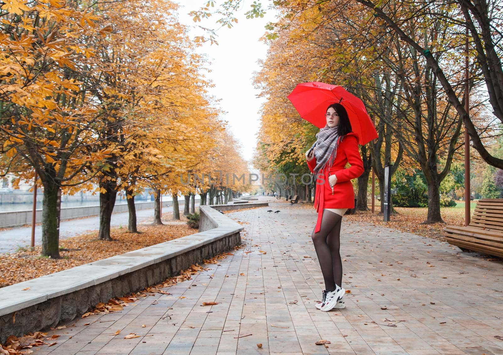 young girl in a red coat with an umbrella standing on the alley by raddnatt