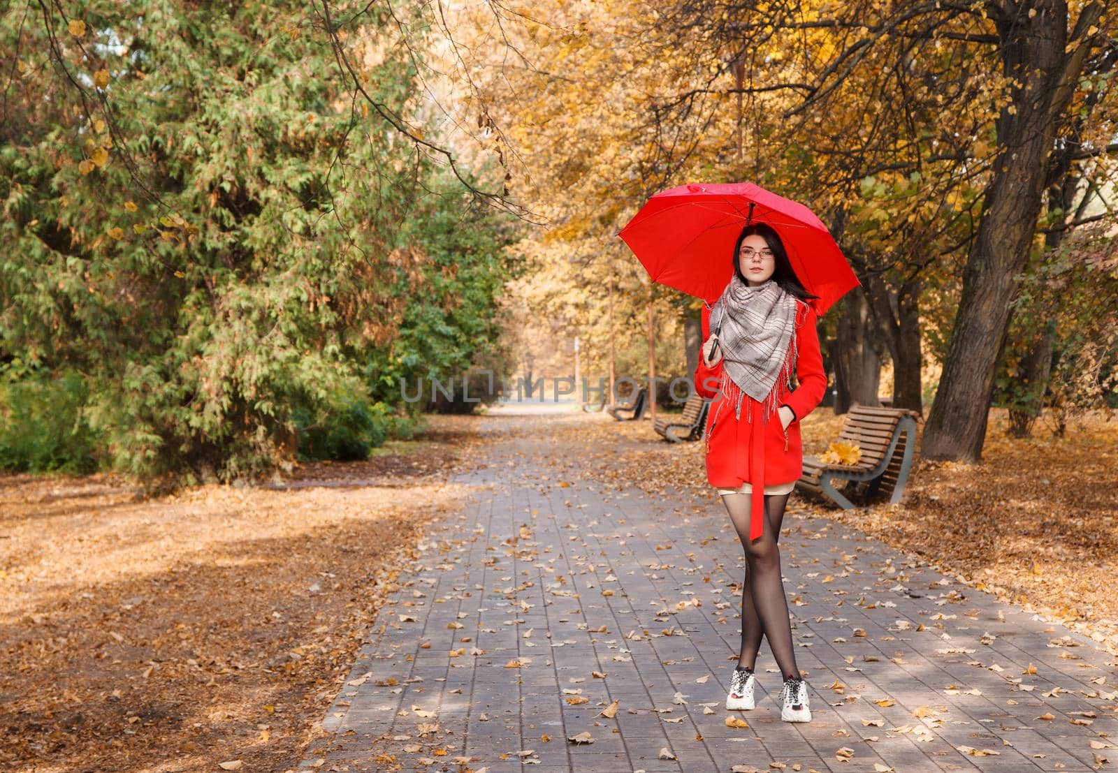 young girl in a red coat with an umbrella standing on the alley by raddnatt