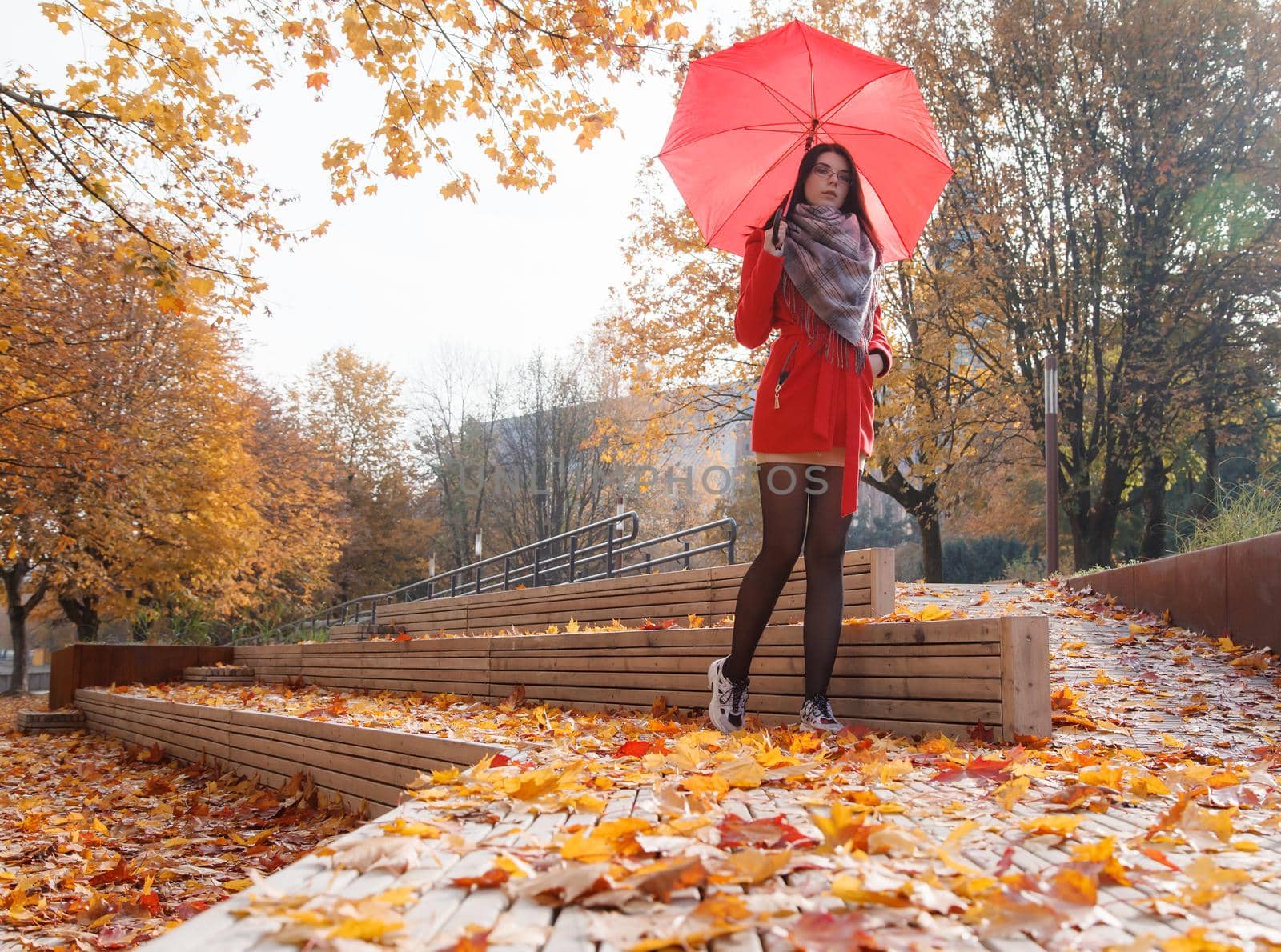 young girl in a red coat with an umbrella standing on the alley by raddnatt