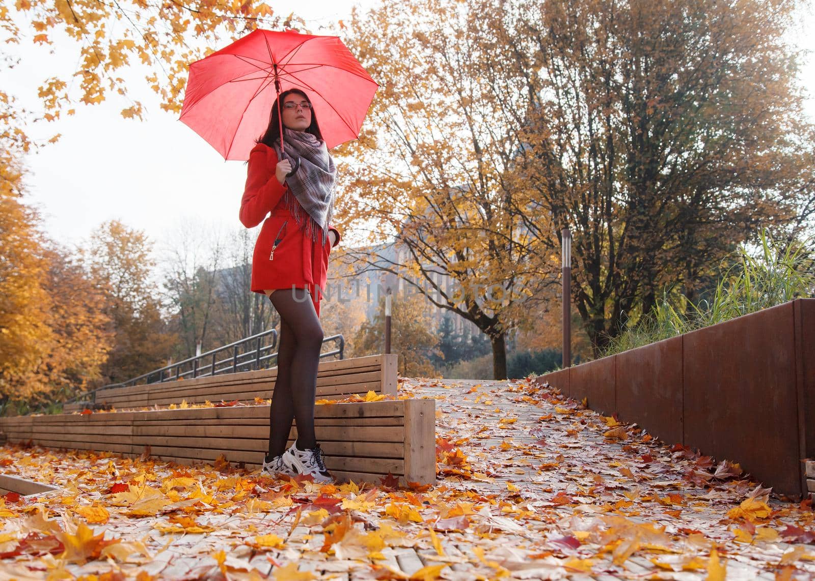 young girl in a red coat with an umbrella standing on the alley by raddnatt