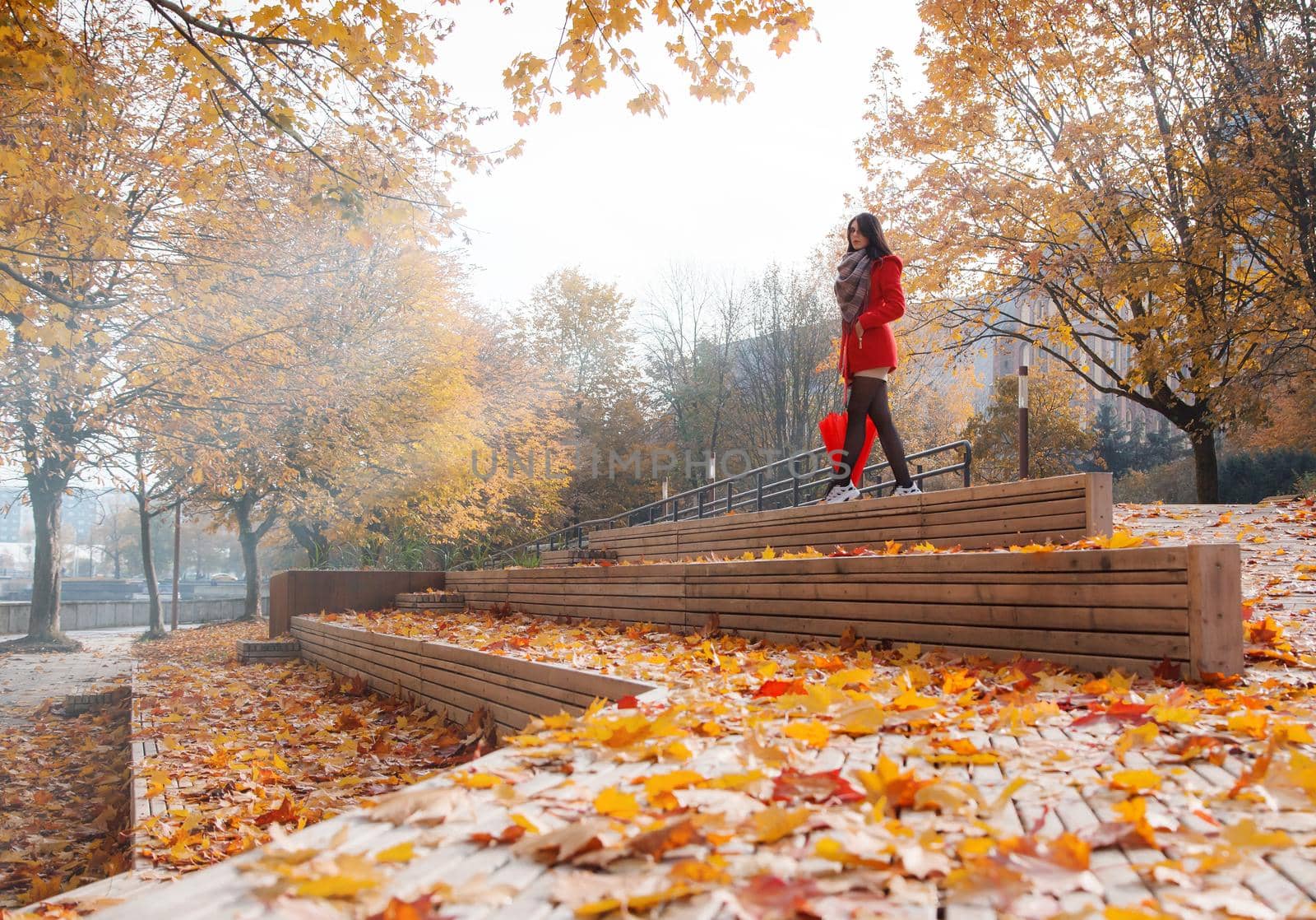 young girl in a red coat with an umbrella standing on the alley by raddnatt