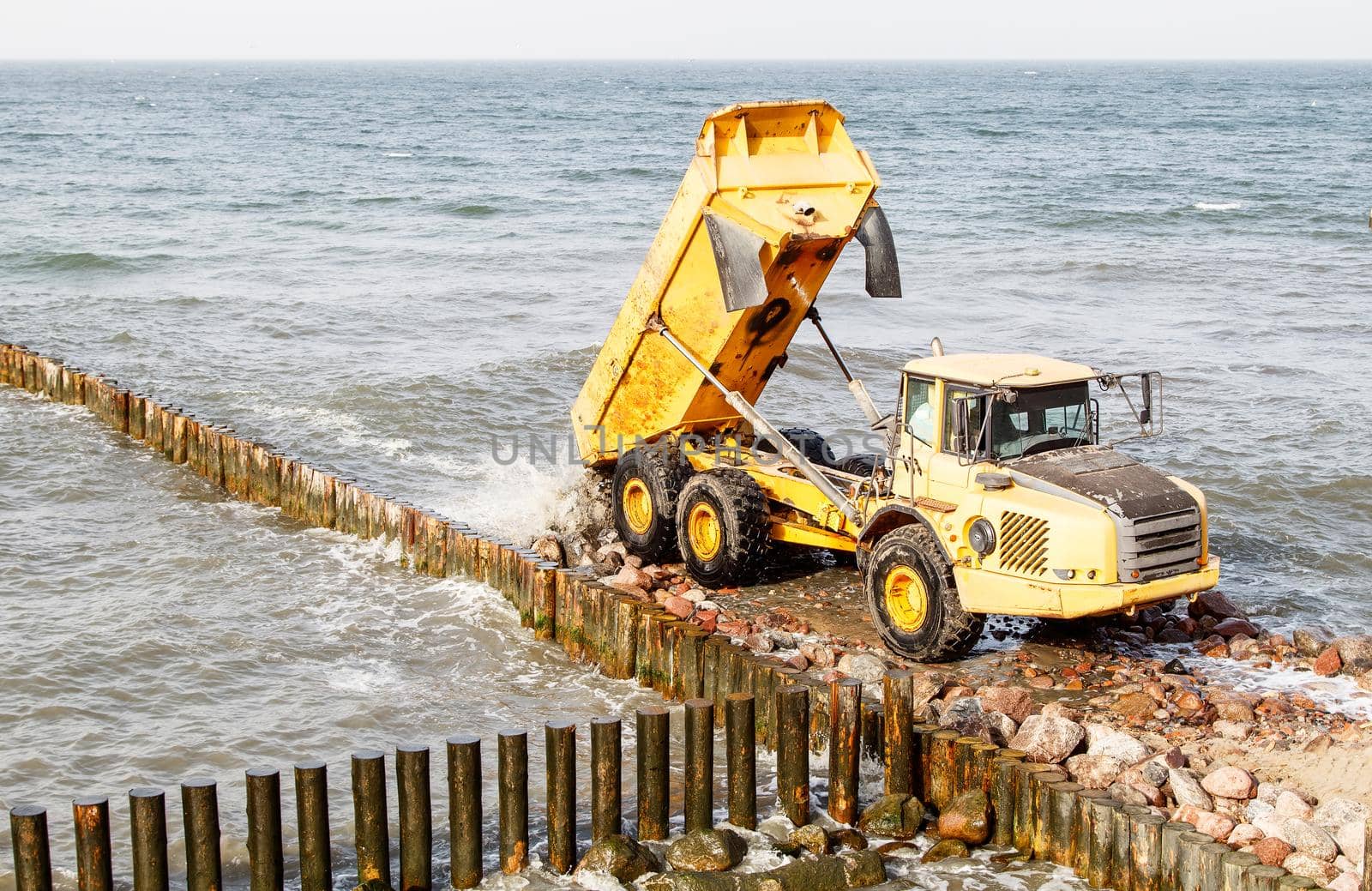 heavy truck during the construction of a breakwater by the sea on autumn day