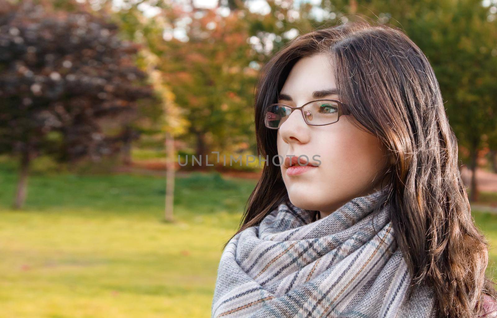portrait of a young beautiful girl in brown jacket in city park on sunny autumn day