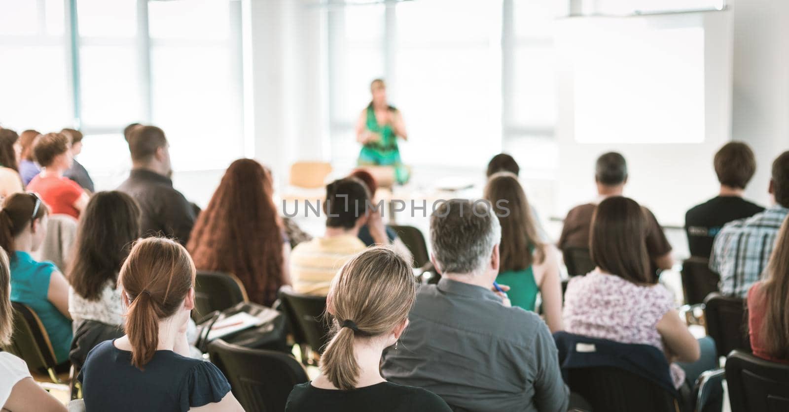 Speaker giving a talk in conference hall at business meeting event. Rear view of unrecognizable people in audience at the conference hall. by kasto