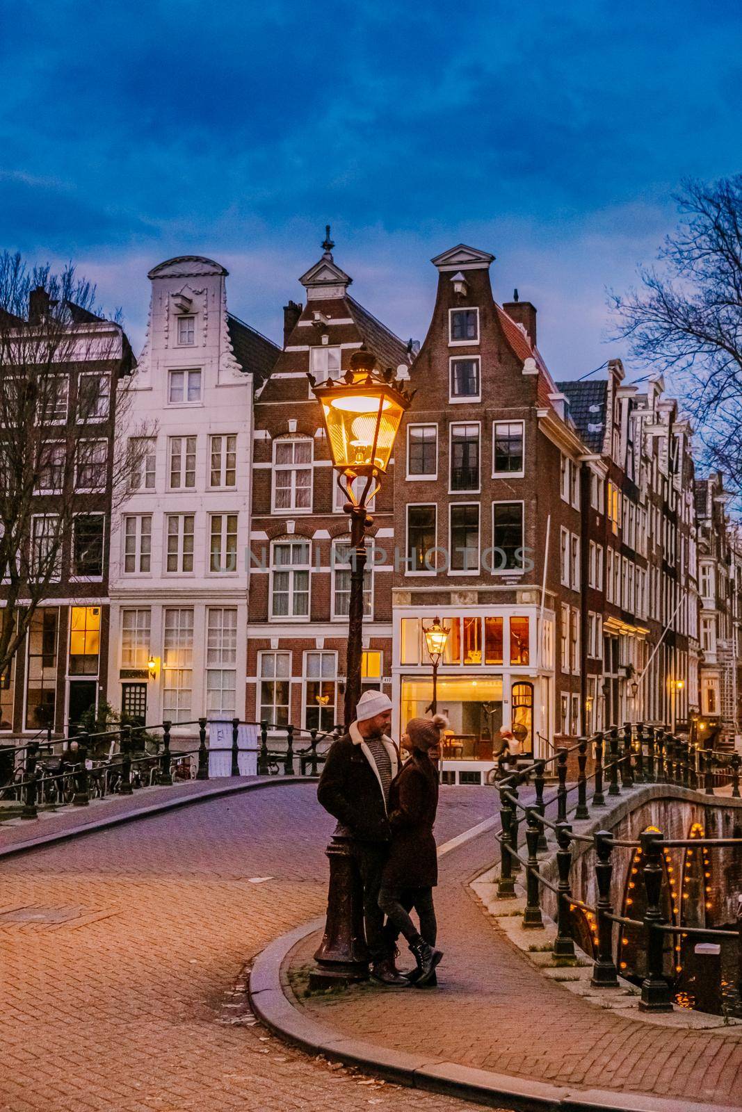 Amsterdam Netherlands during sunset, historical canals during sunset hours. Dutch historical canals in Amsterdam, couple on city trip in Amsterdam , men and woman during evening by the canals