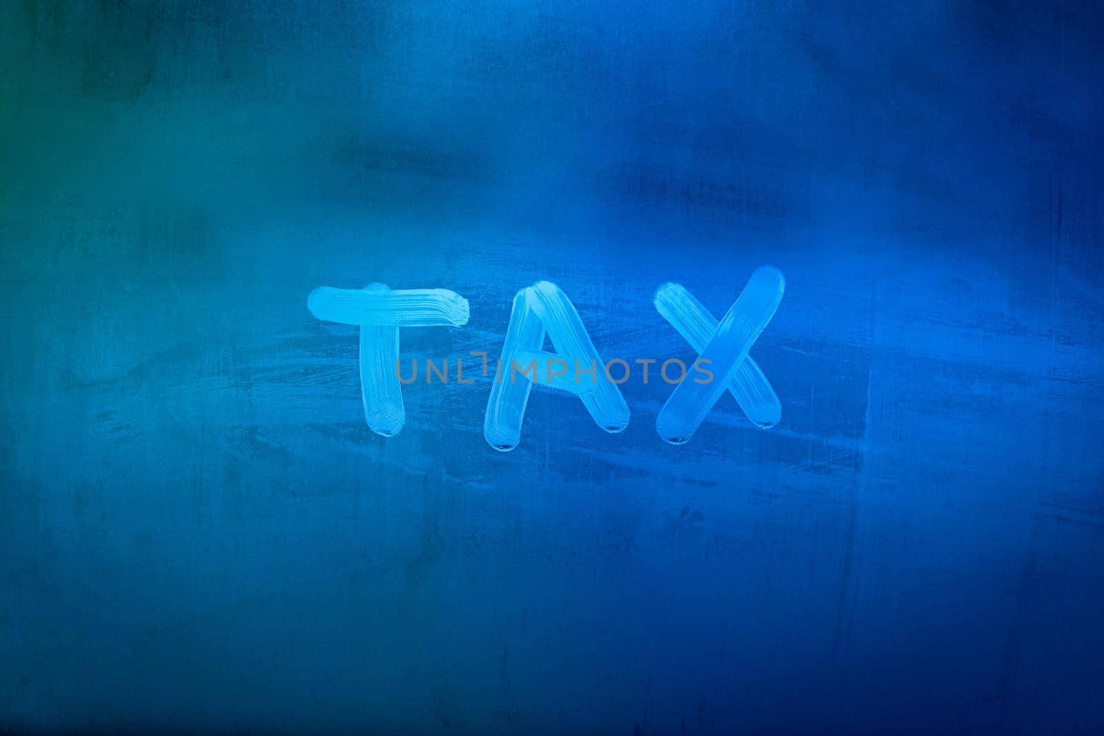 word tax hadwritten on night wet window glass surface with blue colors in blurry background