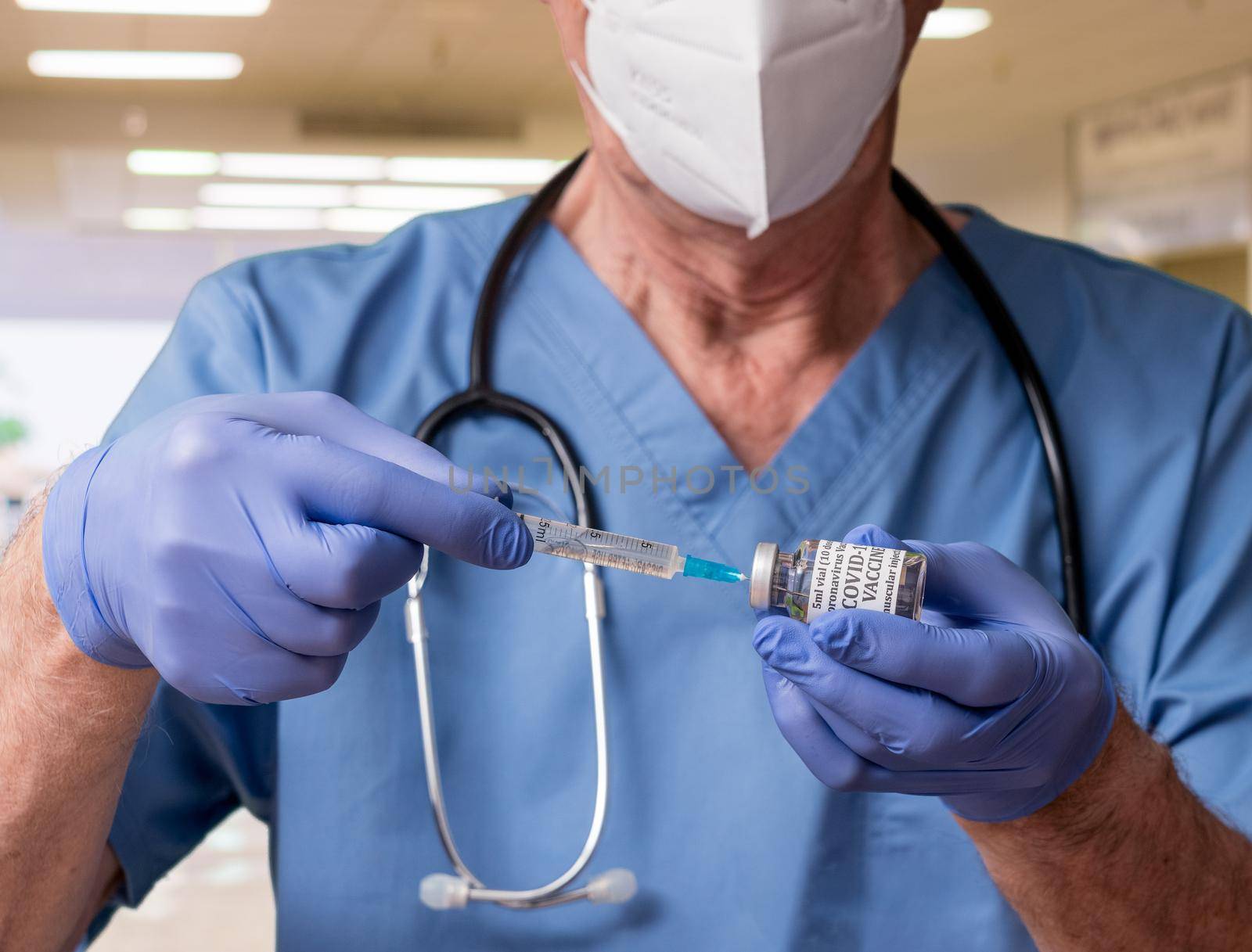 Senior man nurse with syringe preparing a dose of the vaccine in a clinic or doctors office for immunization