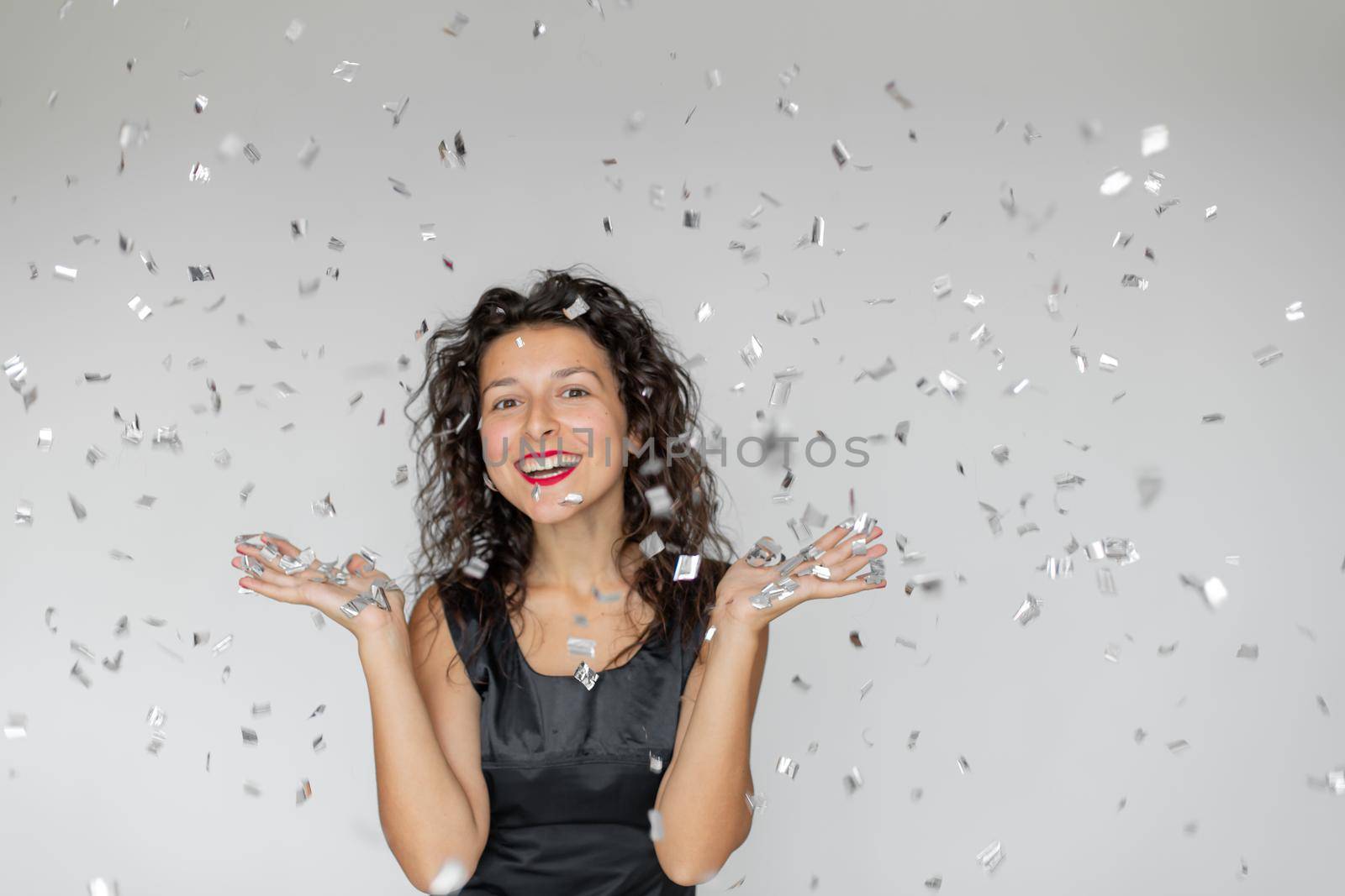 The emotion of success. Happy sexy brunette girl is enjoying celebrating with confetti on a white background.