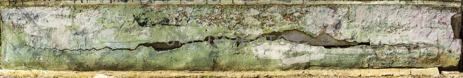 Peeling paint on the wall. Panorama of a concrete wall with old cracked flaking paint. Weathered rough painted surface with patterns of cracks and peeling. Wide panoramic texture for design background by mtx