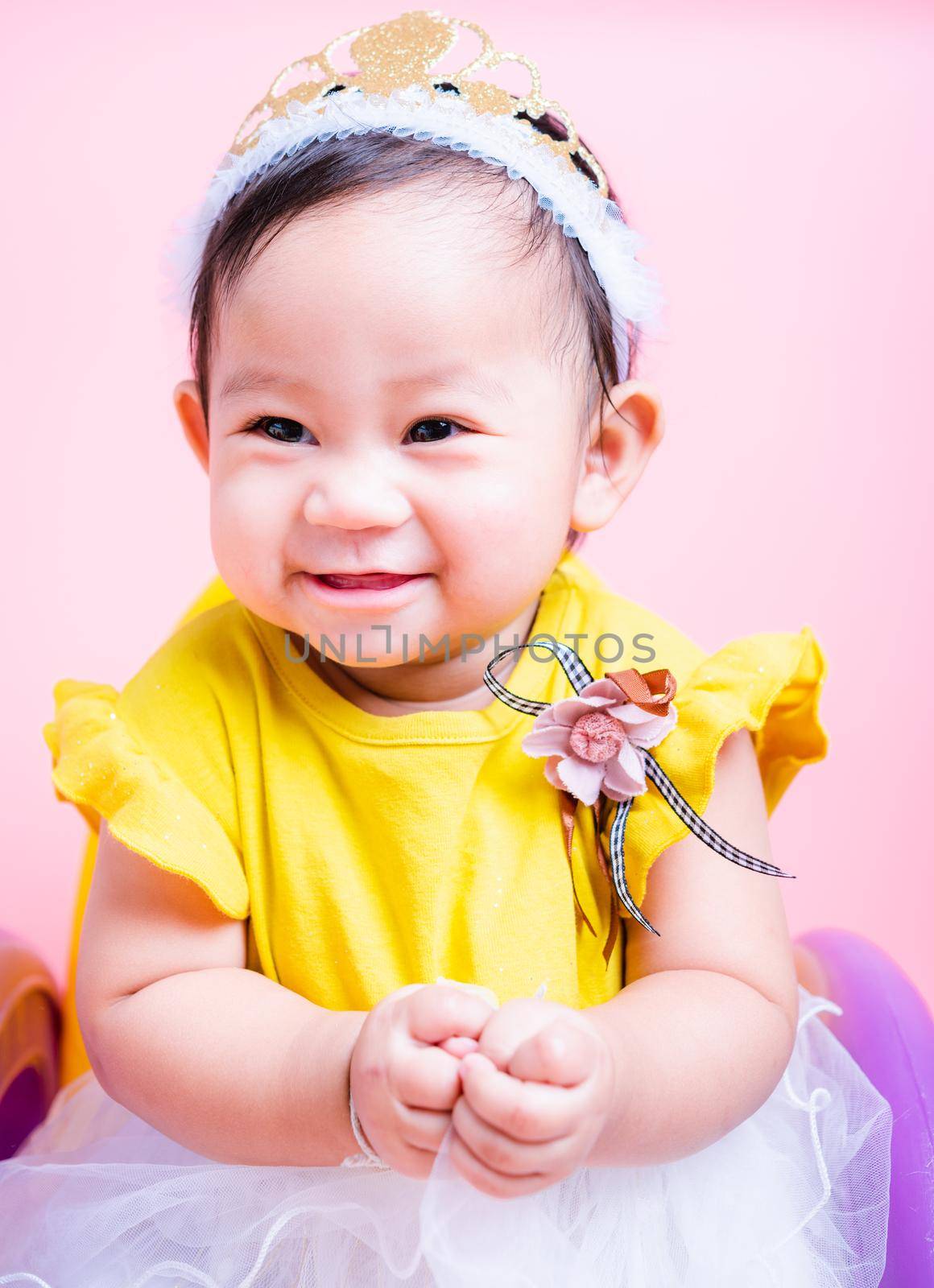 Close up face princess little baby girl in beautiful dress she is smile in studio on pink background, Baby 9 months