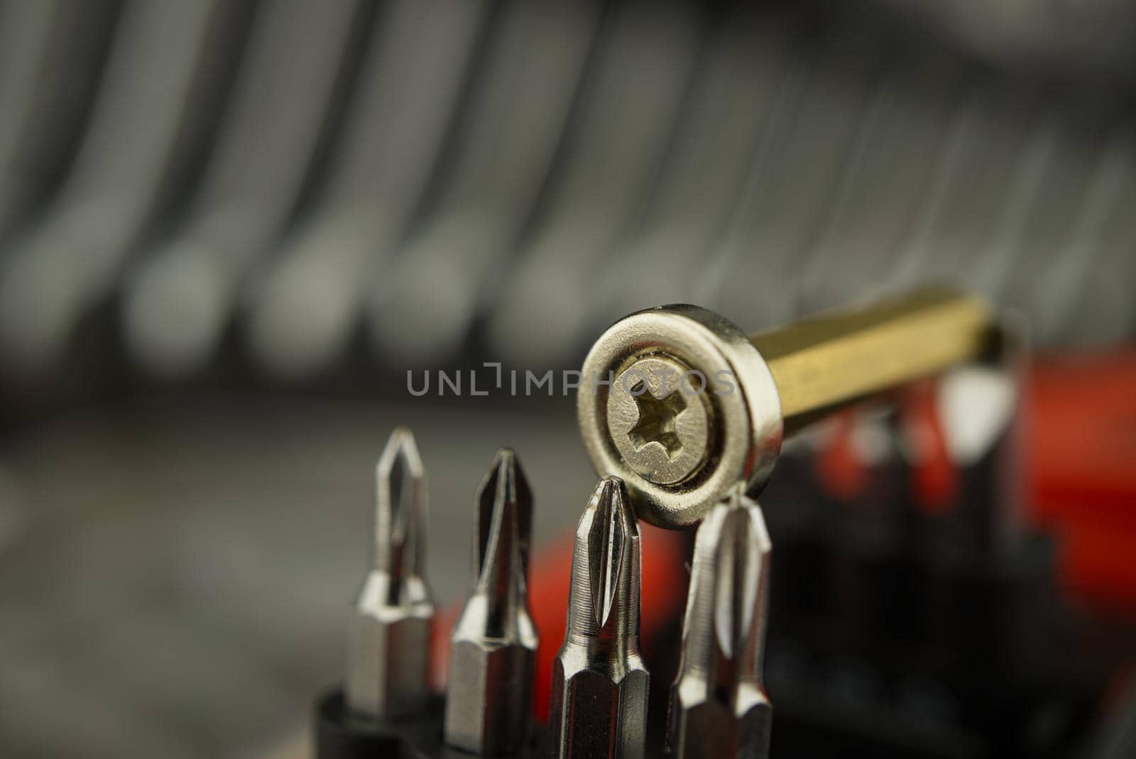 Set of interchangeable screwdriver heads with screw resting on top in selective focus