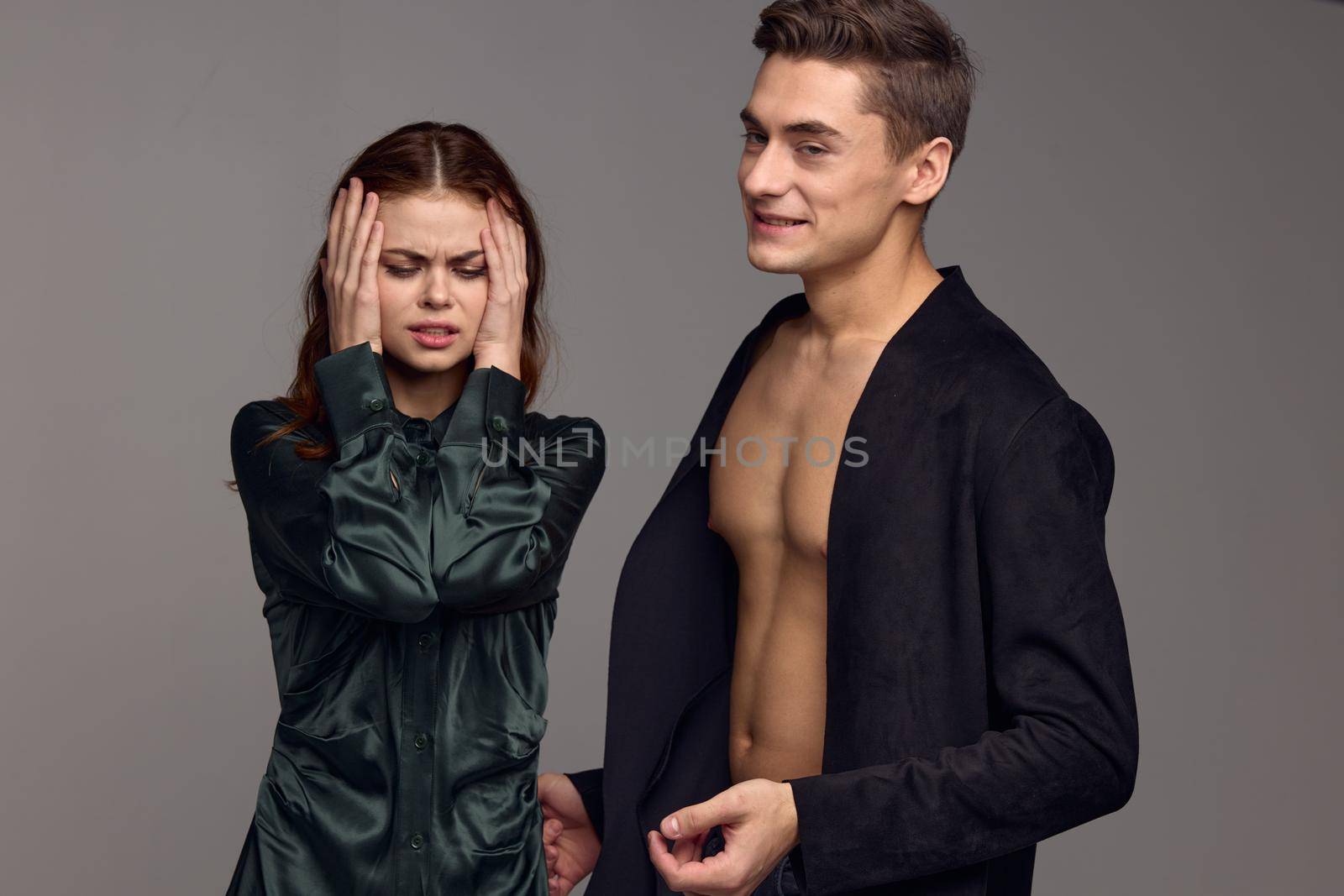 A woman pays touches her head with her hands and a man in a jacket on a naked torso. High quality photo