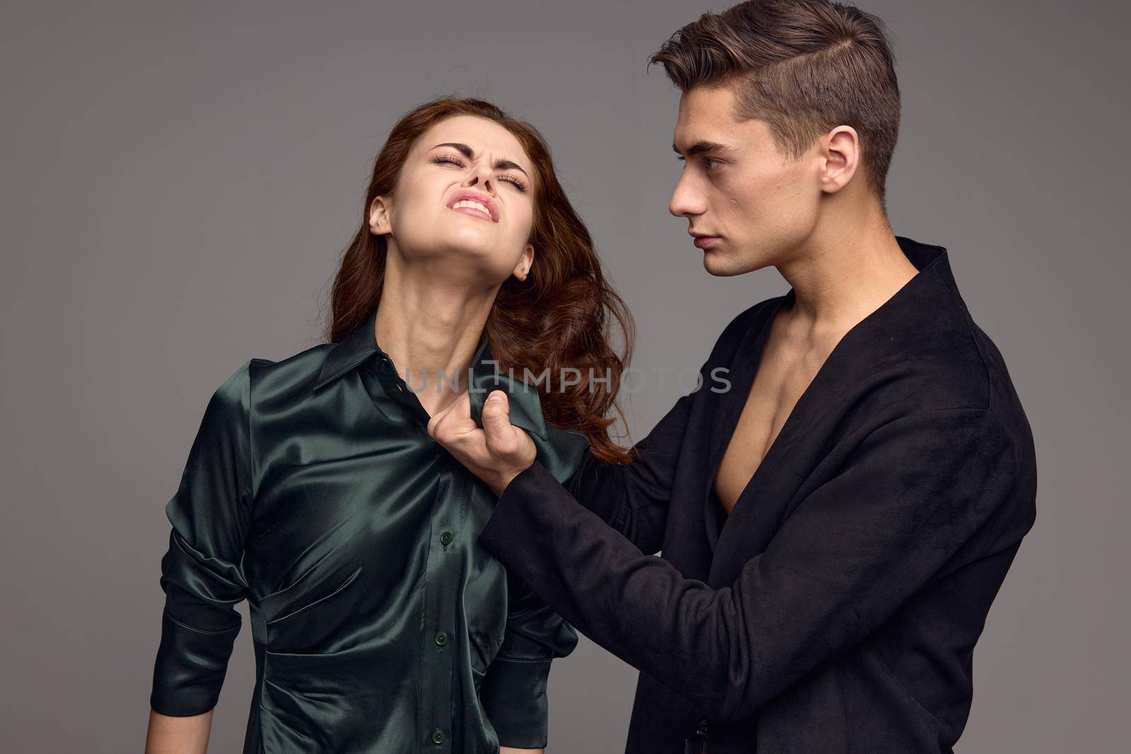 Domestic violence woman in dress conflict gray background man in jacket. High quality photo