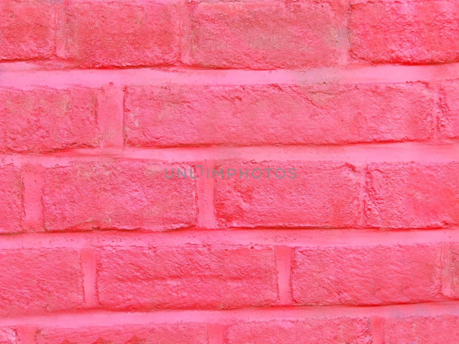 The old brick wall is painted pink in close-up.Texture or background
