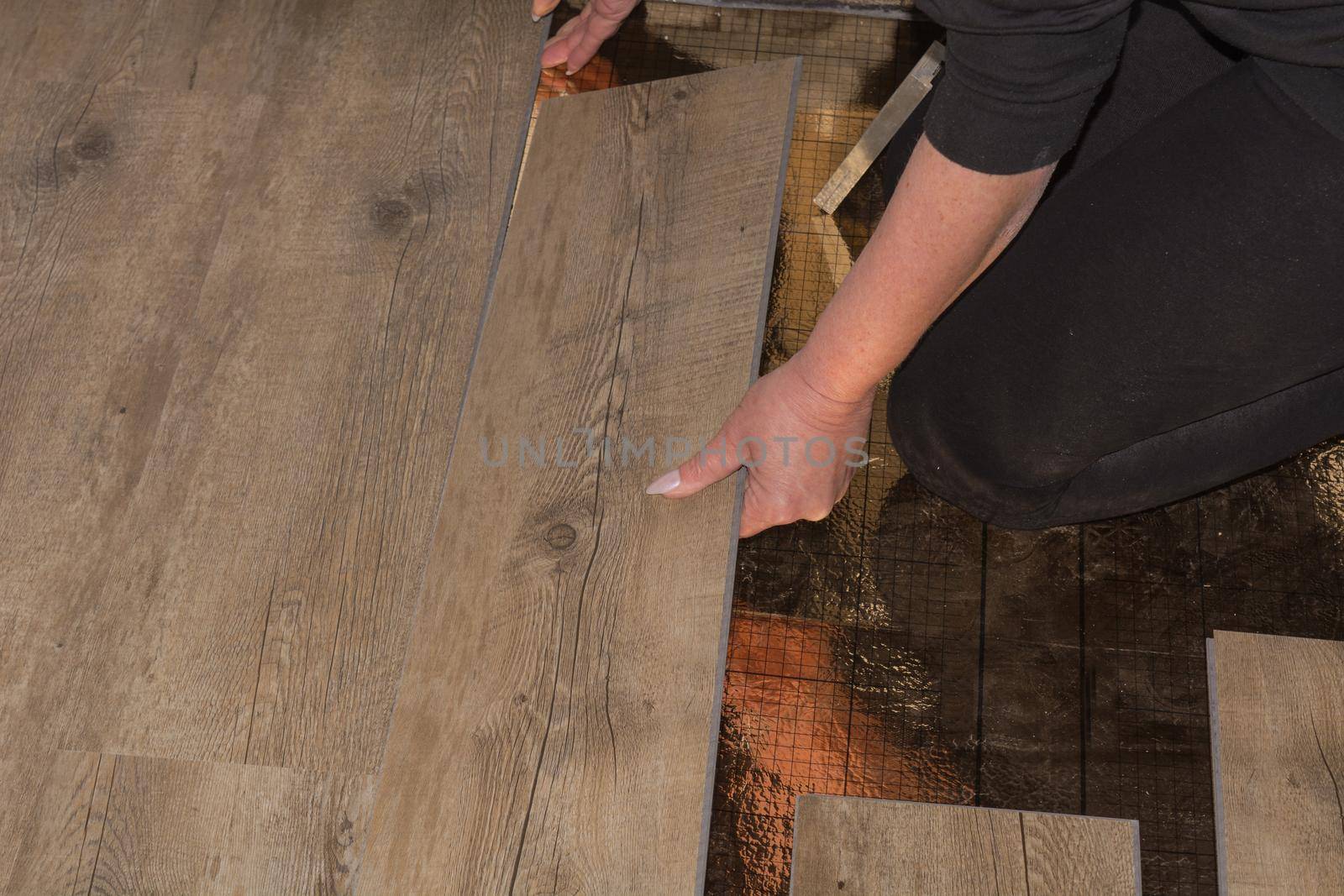 Laying laminate or parquet in the room, worker laying wood or linoleum laminate on the floor and marking the laminate length