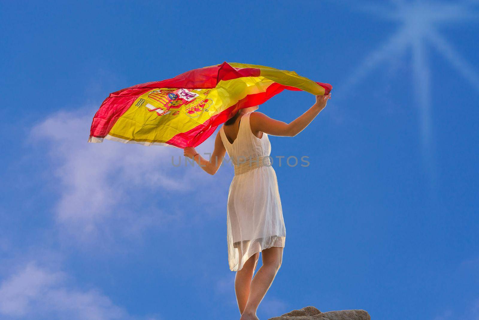 Young Woman with Spanish flag in front of dramatic sky.Noise