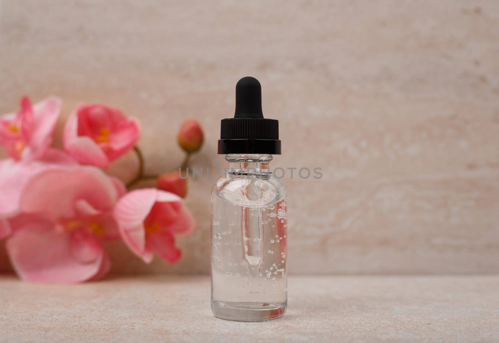 Selective focus, liquid gel or skin serum for daily or anti aging treatment against marble background with flowers by Senorina_Irina