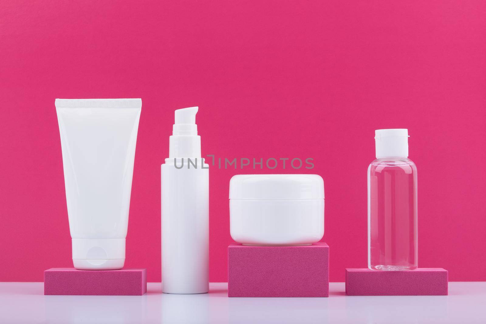 Still life with set of cosmetic products on pink podiums against bright pink background. Concept of beauty routine and skincare. High quality photo