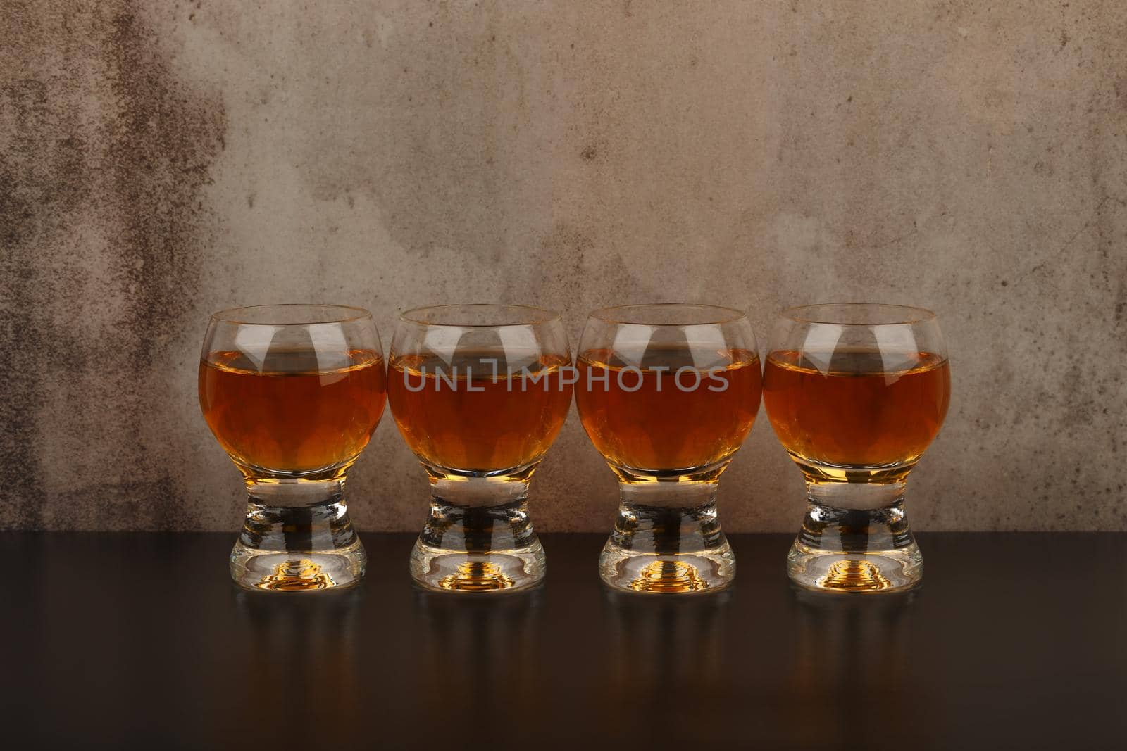 Set of four shot glasses with liqueur in a row on black table with reflection against marble background with copy space by Senorina_Irina