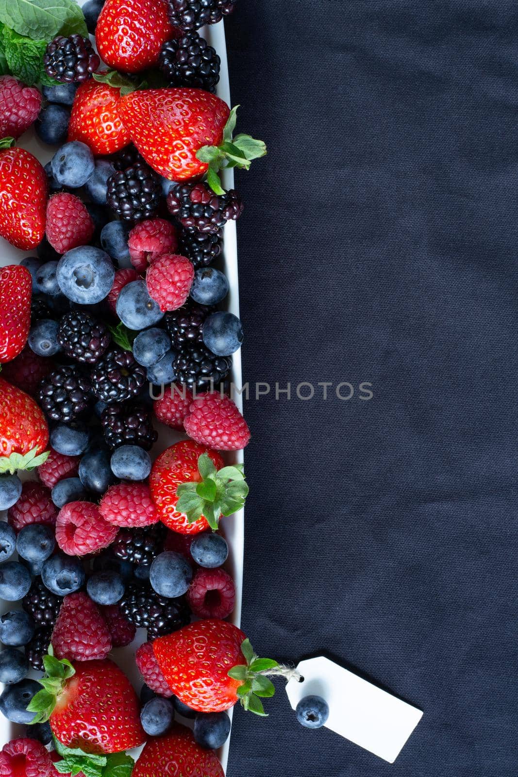 Strawberries, blackberries, rasberries, green mint on canvas black bakground. Mock up, menu, cafe poster concept