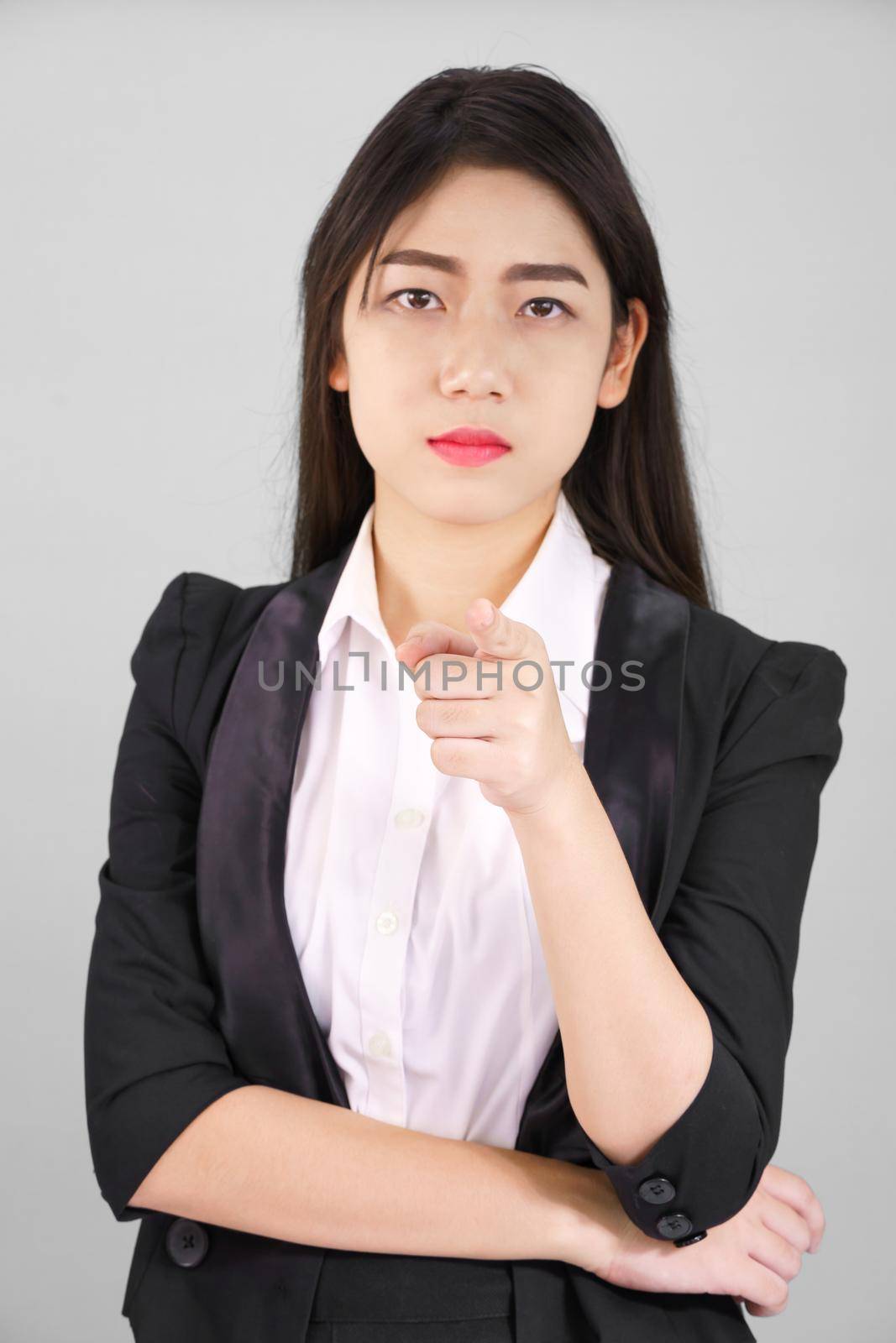 Asian woman in suit looking at camera and pointing finger on gray background