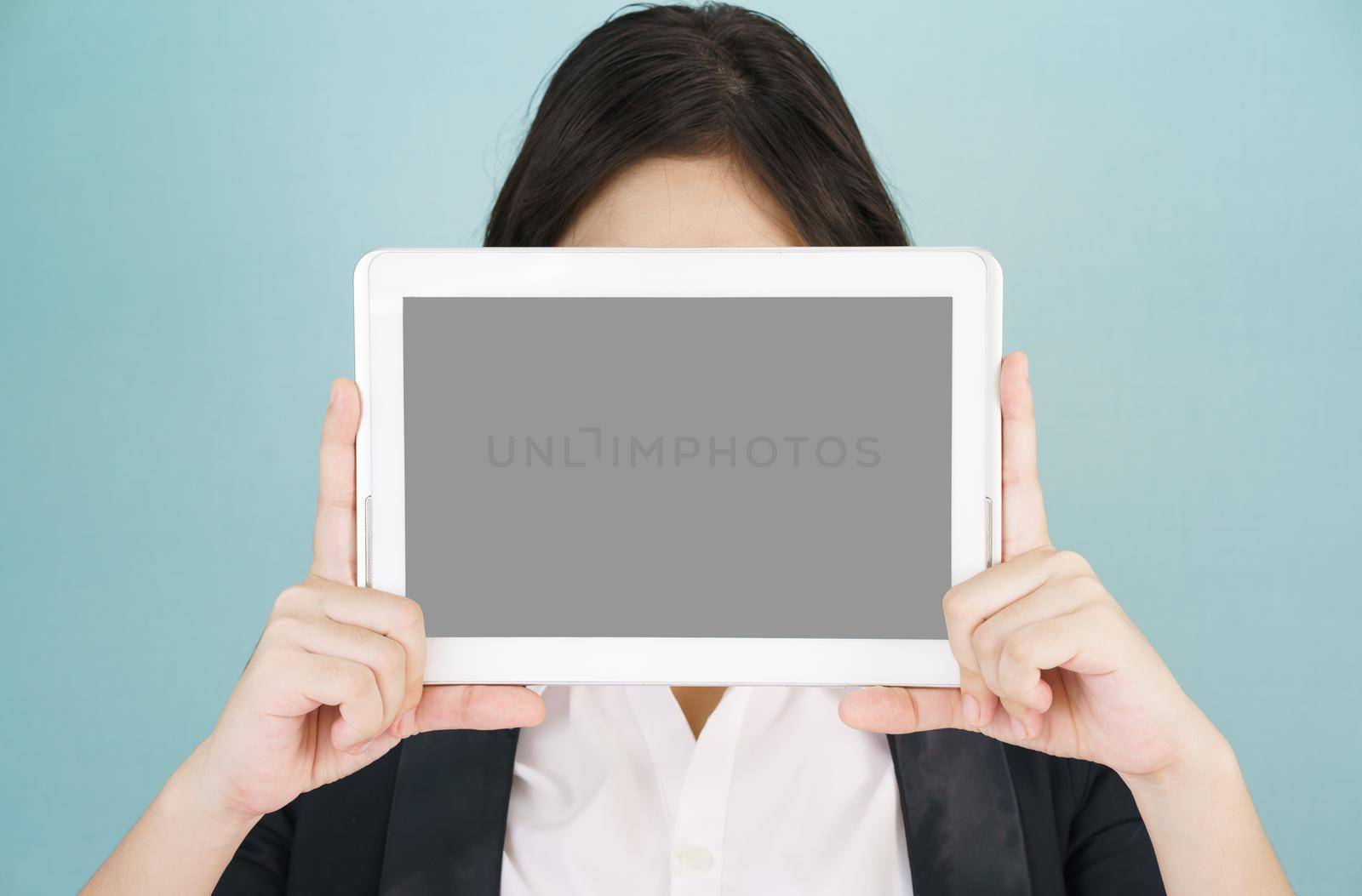Young asian women in suit holding her digital tablet standing against green background