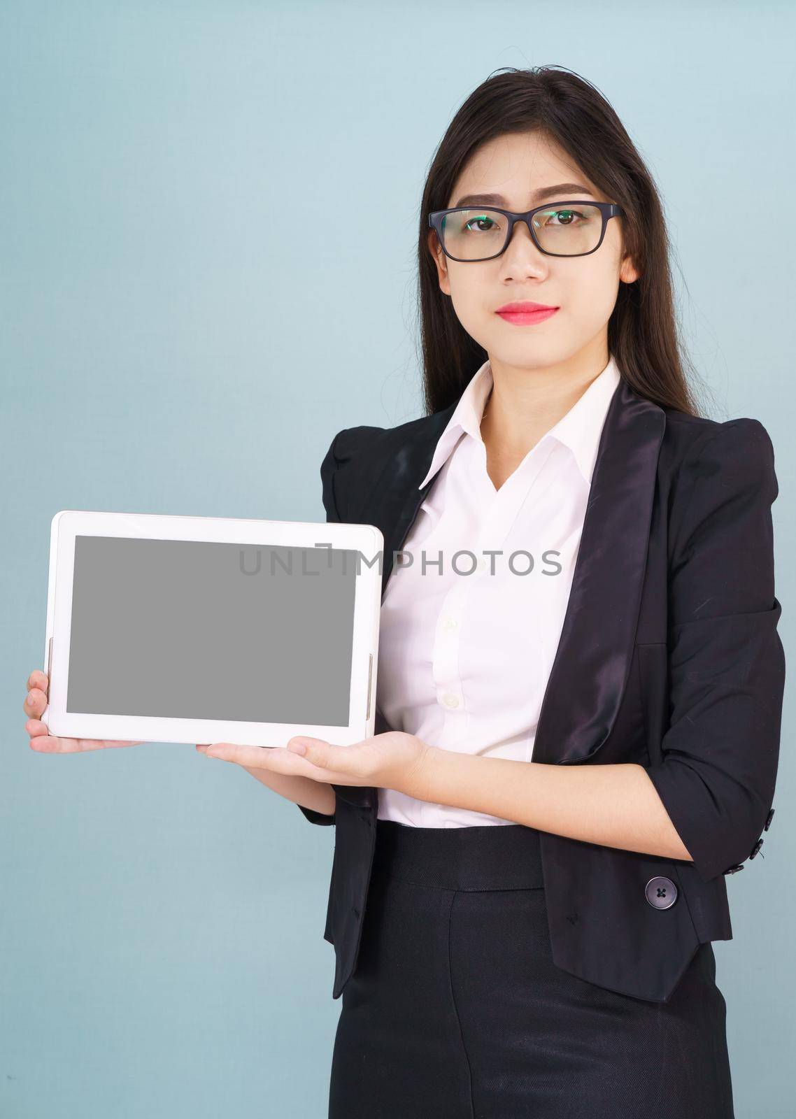 Young asian women in suit holding her digital tablet standing against green background