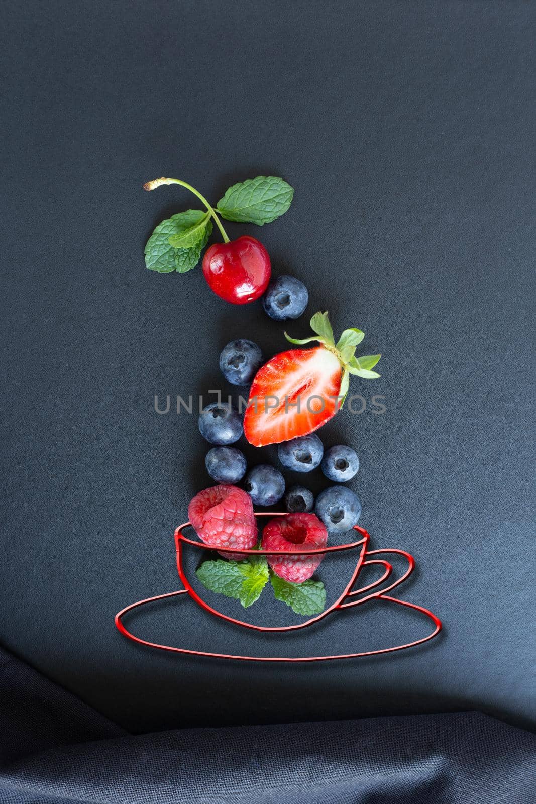 Summer fruits, berries and mint in chalk painted cup of tea on black background. Conceptual healthy, vitamin, dietary food. Vegan, vegetarian and detox food and drinks. Menu mock up for cafe, poster concept