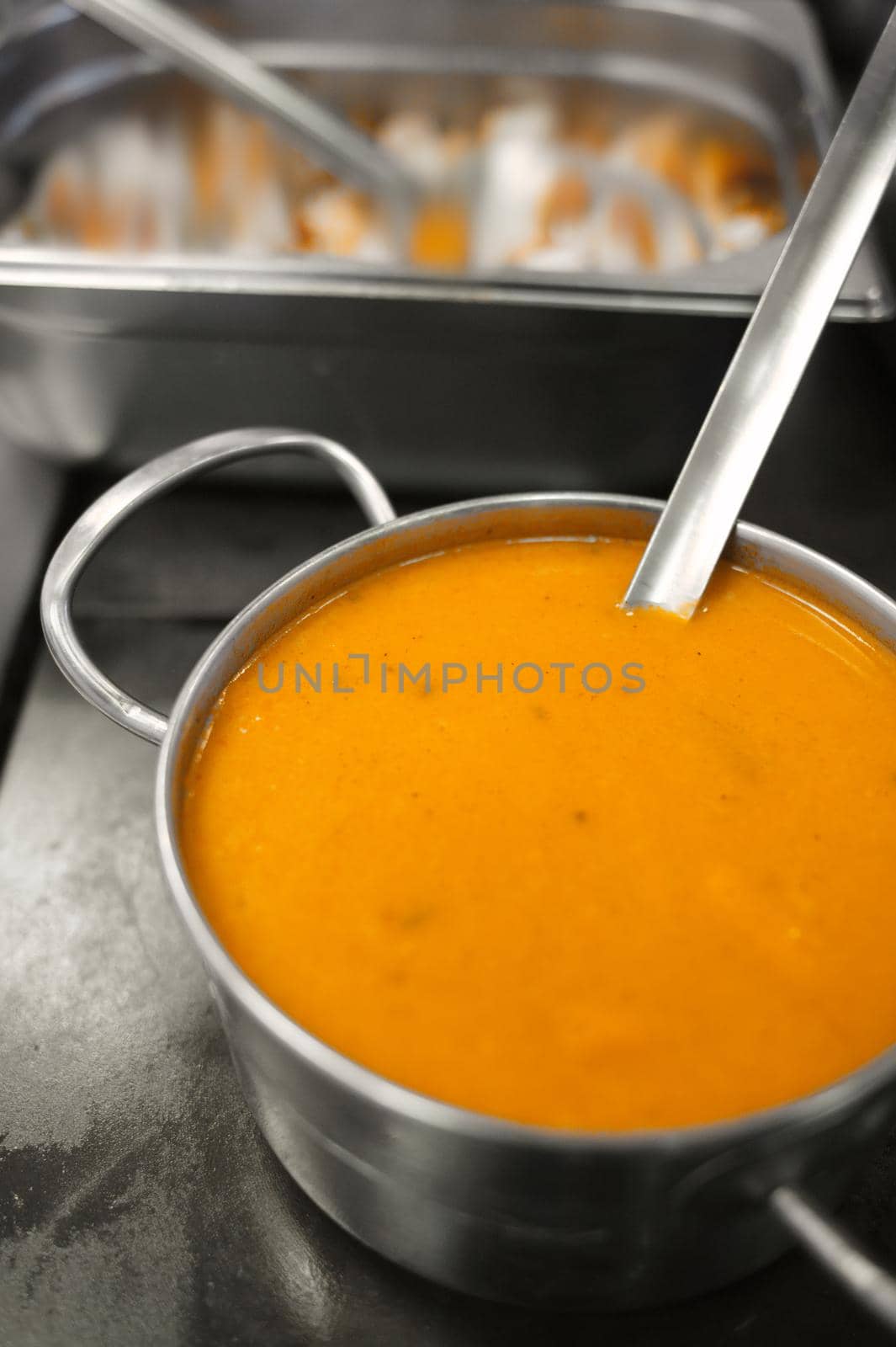 Yellow soup in a metal pot. Preparing lunch in the dining room. Exotic stew. Food in a steel metal dish. Space for copying. Blank for the designer