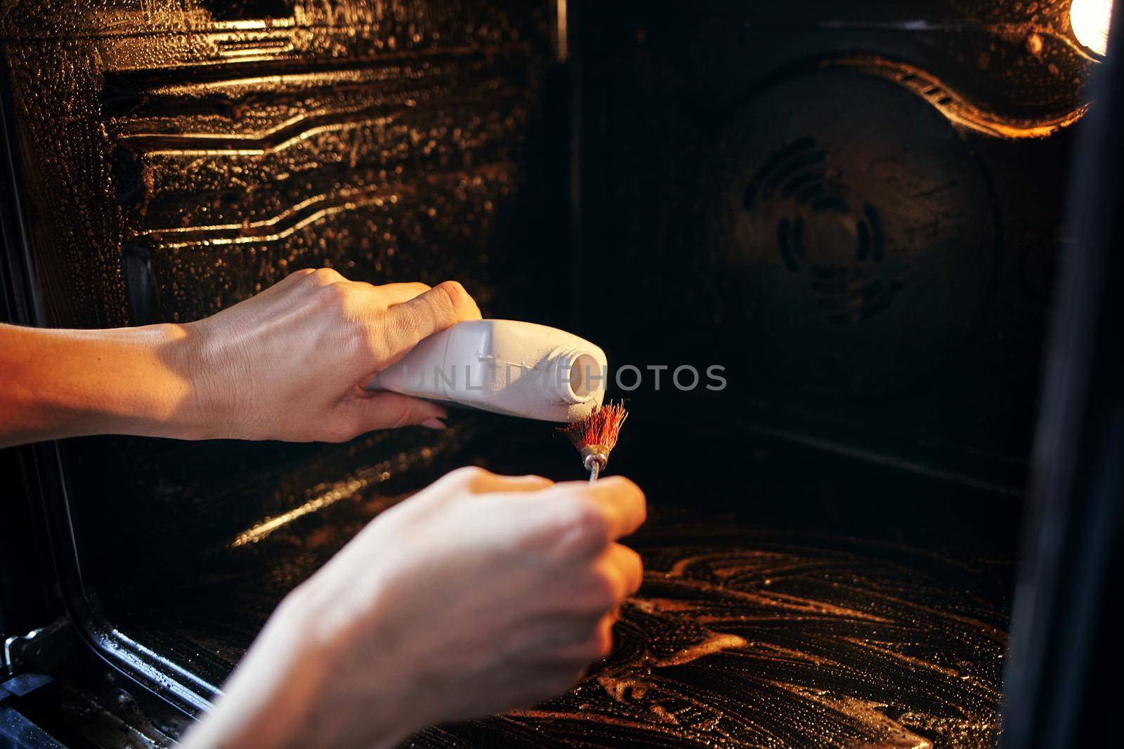 A tool for cleaning the oven and gas stoves. A woman cleans the oven from fat and pollution. by SergeyPakulin