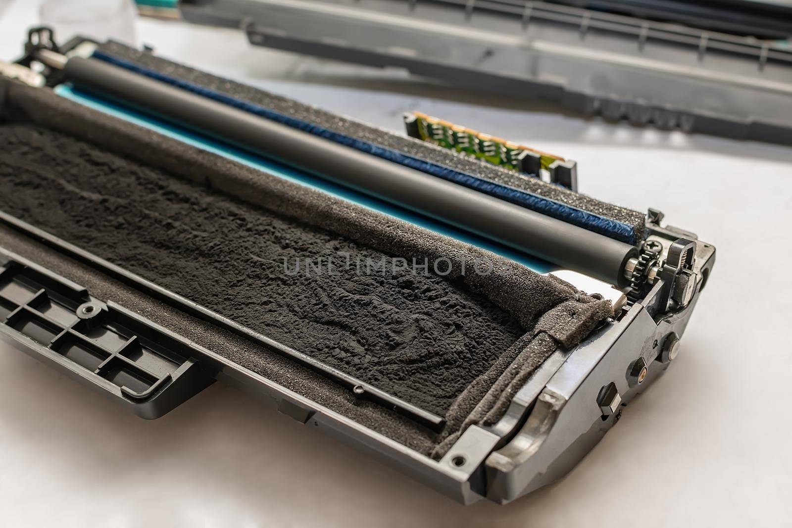 the cartridge from the laser printer, filled with toner, paint, with a chip, lies disassembled on a white table