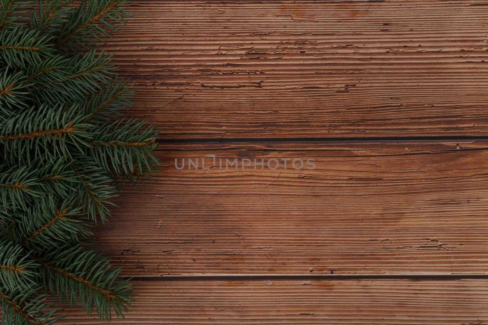 Dark brown wooden table with Christmas tree at the left side and space for text. The concept of New Year, Christmas and winter holidays. Horizontal photo, studio shot, no people