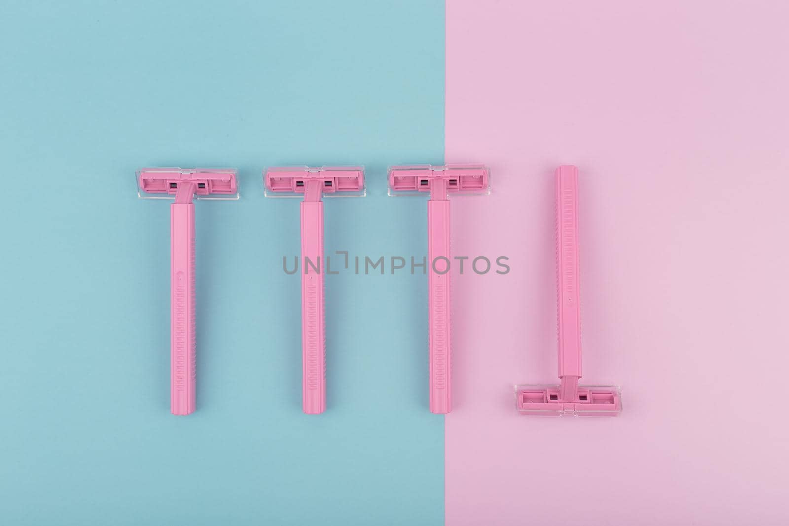 Pink plastic razors on pink and blue background by Senorina_Irina