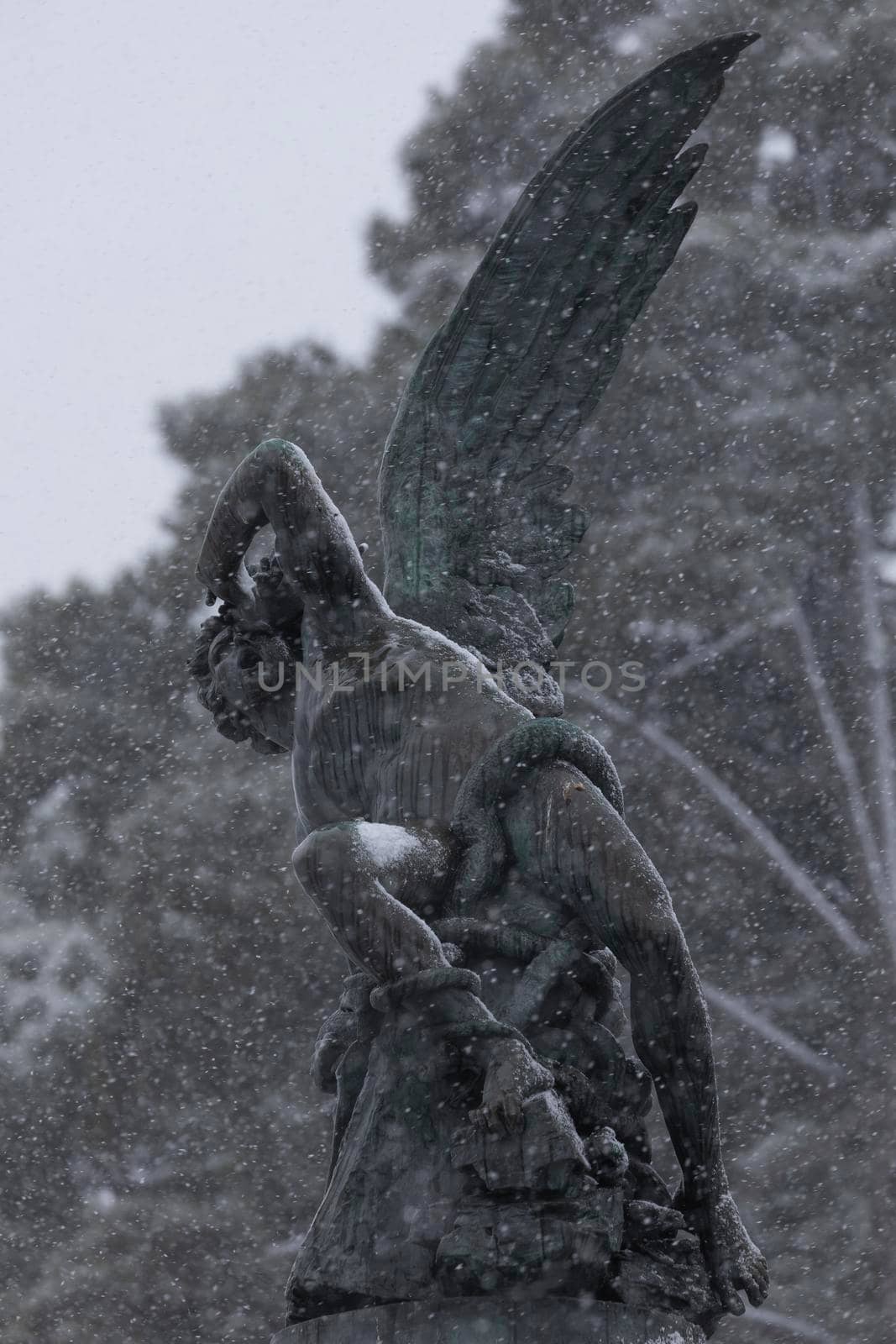 Bronze sculpture, Fallen Angel fountain, on a snowy day, Madrid. by alvarobueno