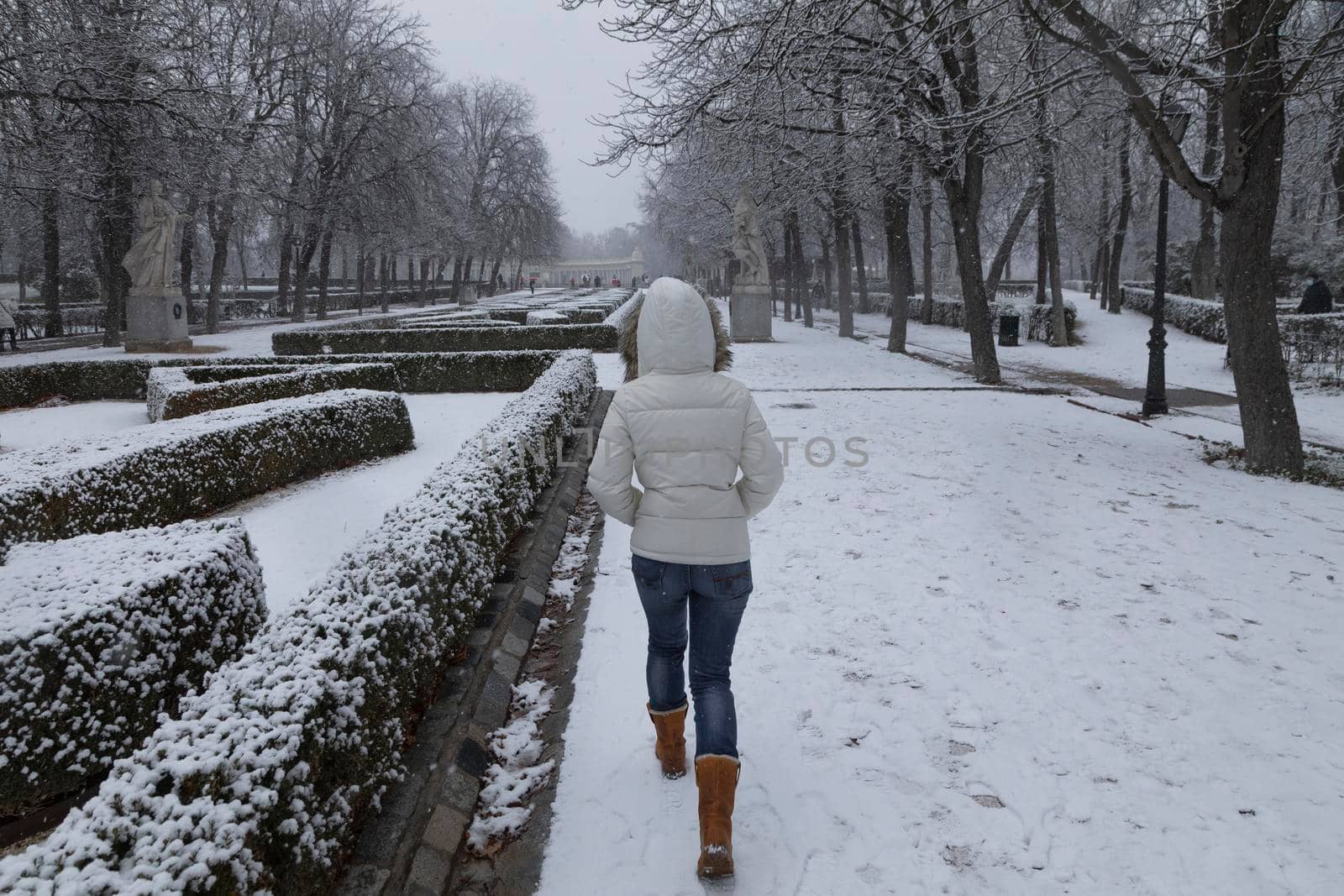 Madrid, Spain - January 07, 2021: A young girl enjoys a walk through the Buen Retiro park in Madrid, in the middle of a snowy day, due to a wave of polar cold.