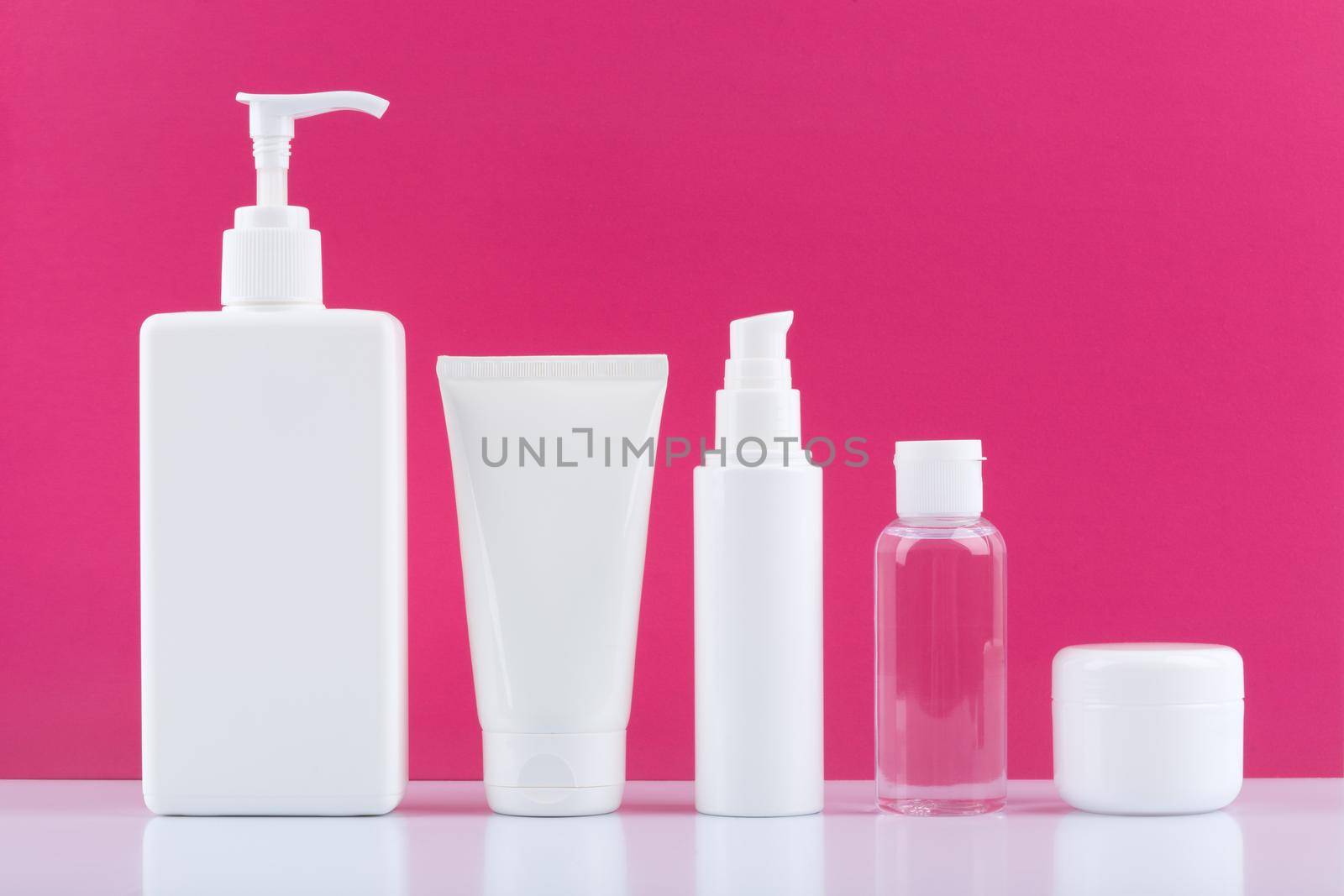 Bright pink still life with set of cosmetic products for skin and body care against pink background.Concept of set for skin and body care, hygiene or anti aging treatment