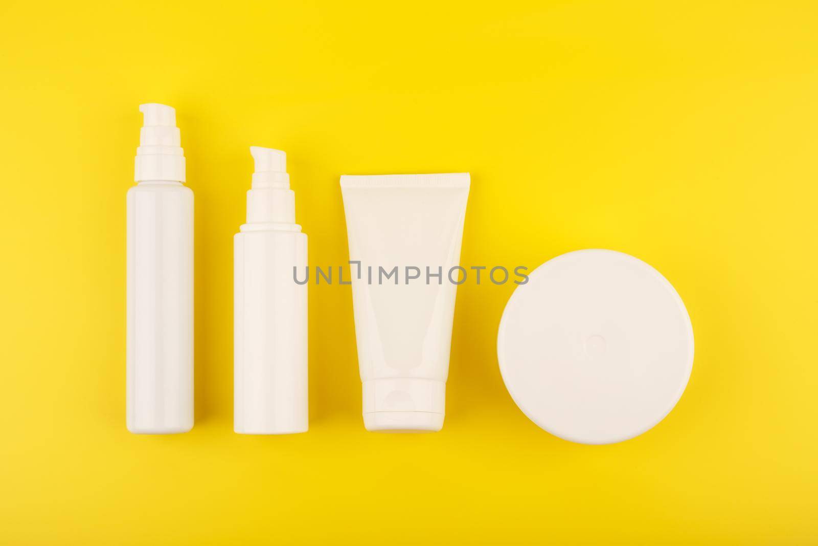 Flat lay with set of cosmetic products for skin and body care on bright yellow background by Senorina_Irina