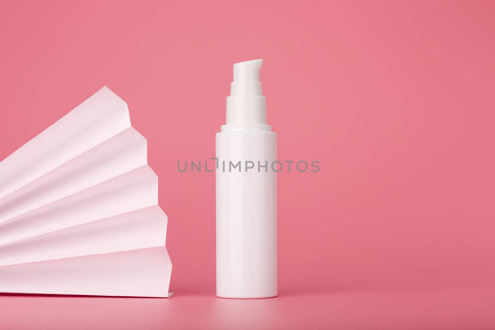Laconic still life with face cream on pink background decorated with white waver with space for text. High quality photo
