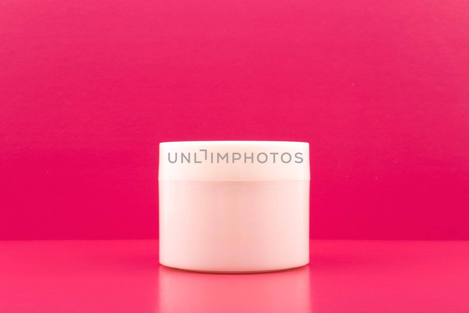 Simple still life with white jar with mask, cream or balm on pink table against pink background with copy space  by Senorina_Irina