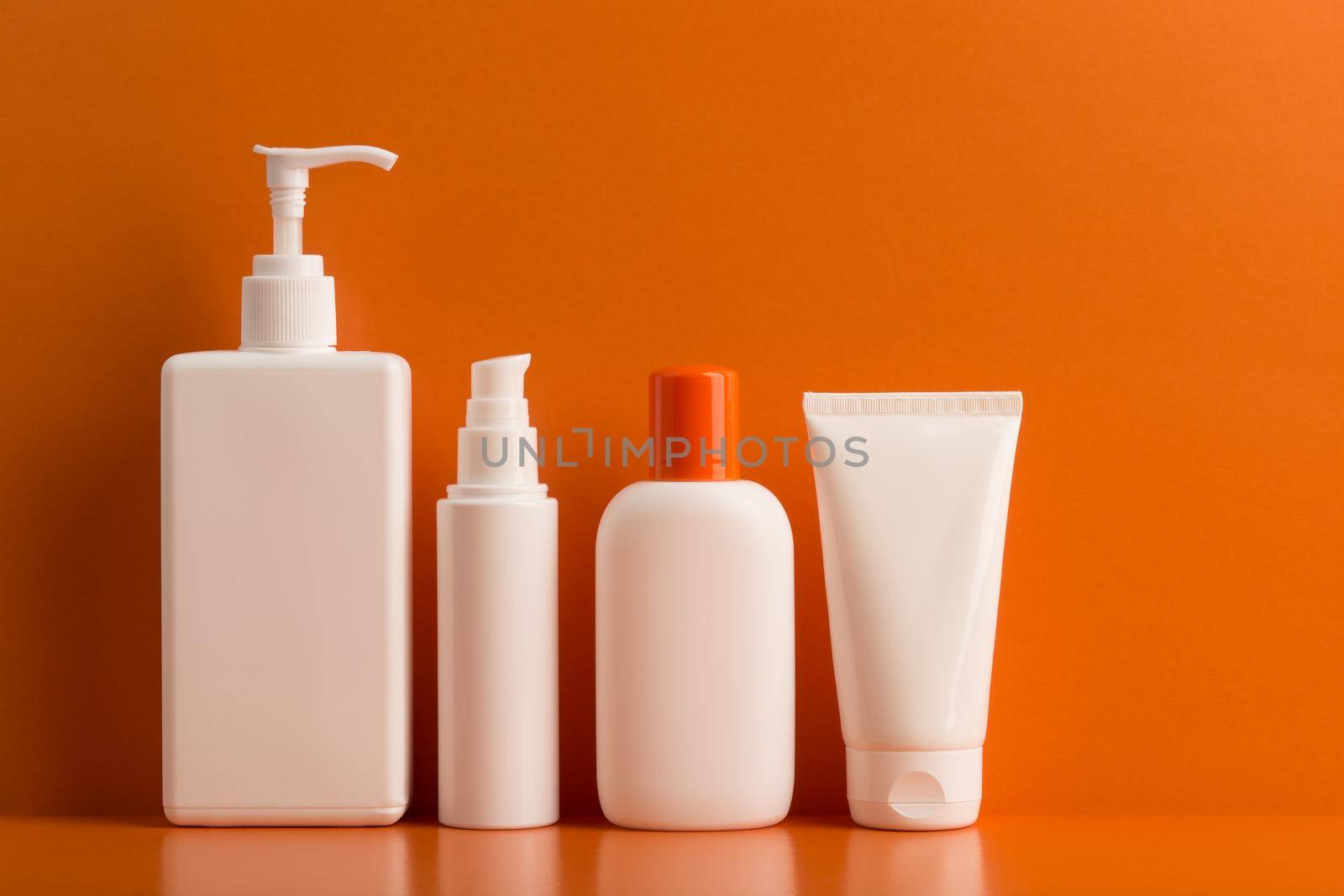 Set of sunscreen cosmetic products for skin and body care in summer against orange background. by Senorina_Irina