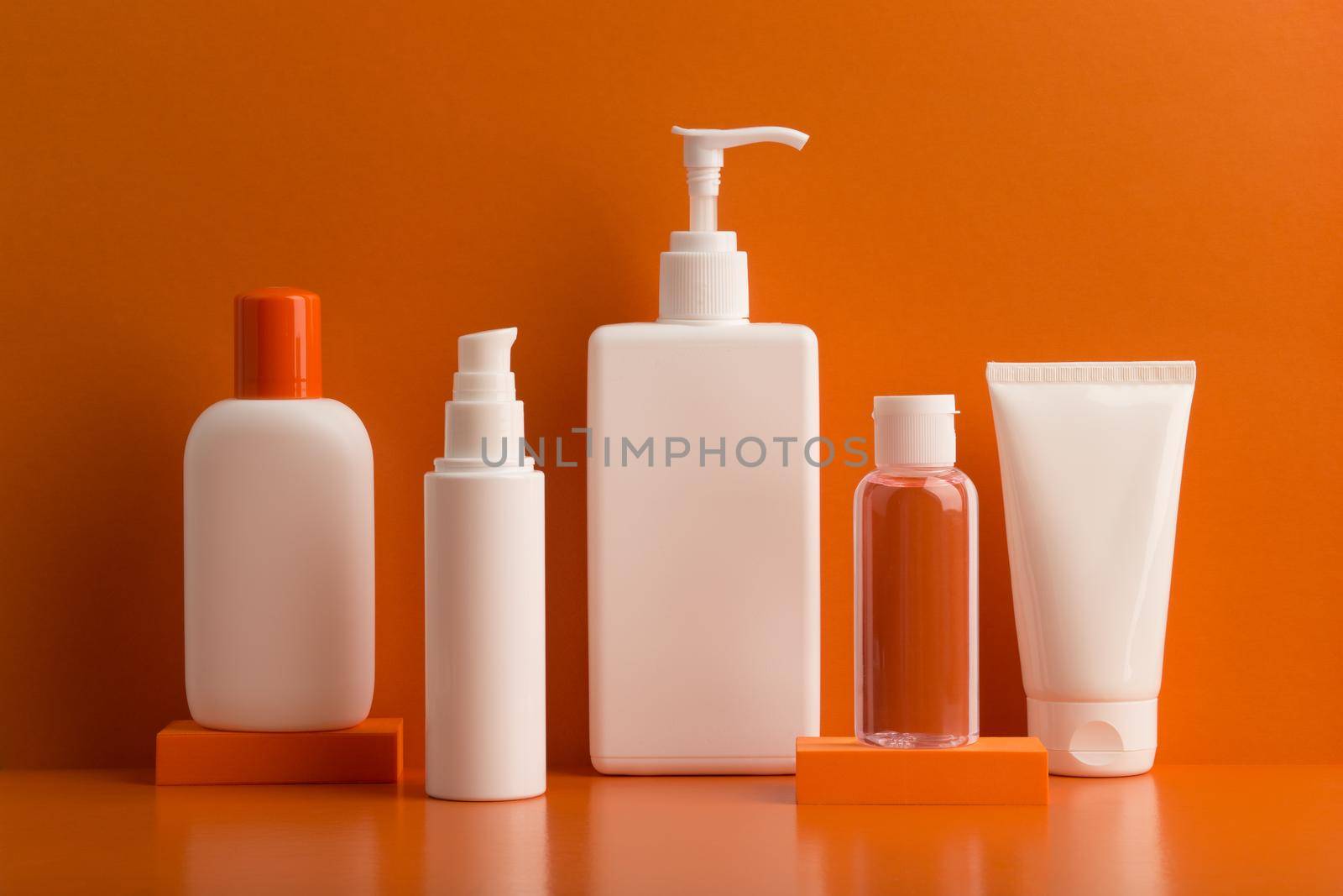 Set of cosmetic products for skin and body care against orange background. Concept of summer or regular skincare by Senorina_Irina