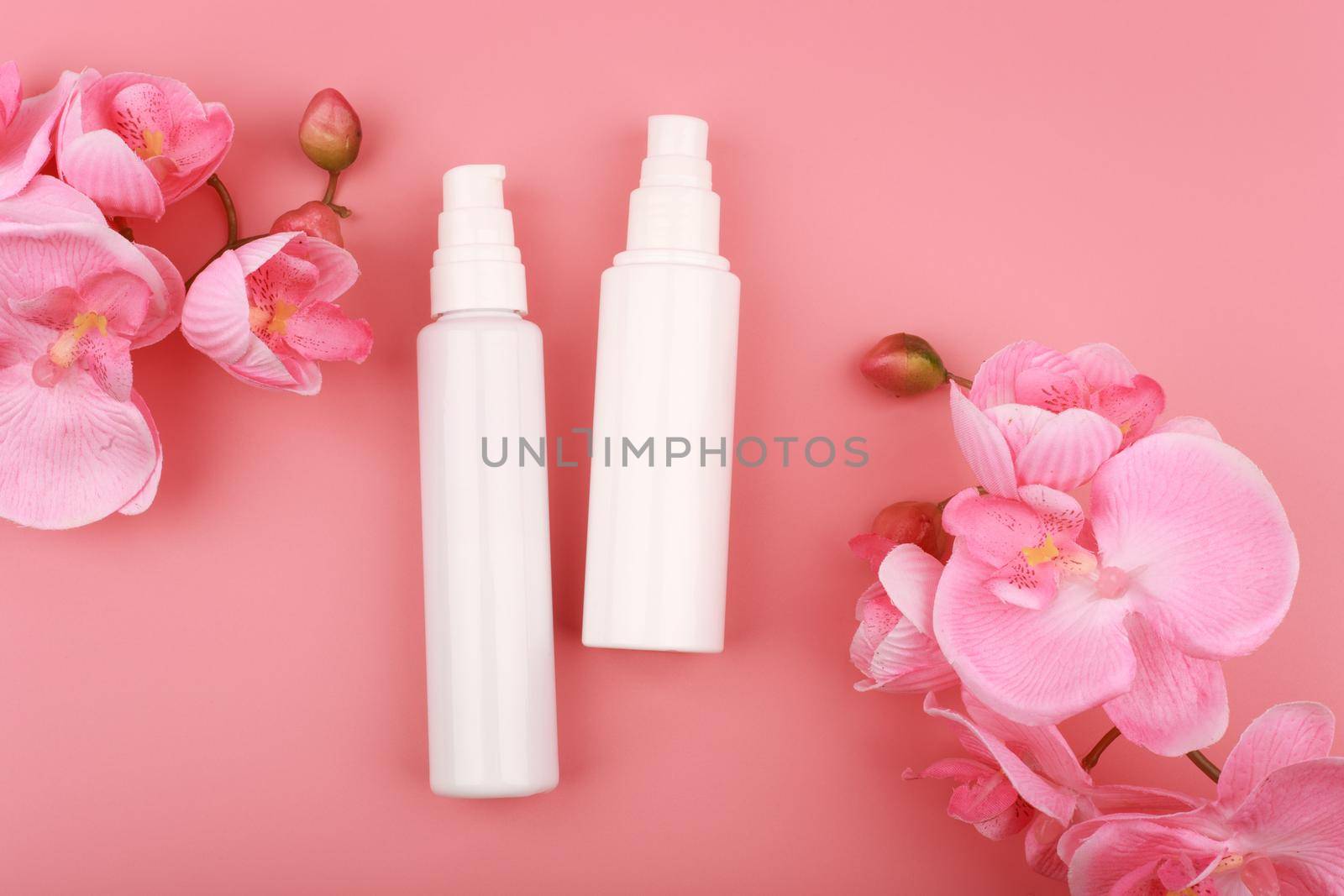 Flat lay with two creams on pink background with flowers. Concept of skin care and beauty or daily skin routine