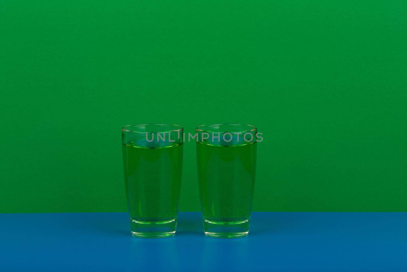 Two green drinks on blue table against green background with space for text by Senorina_Irina