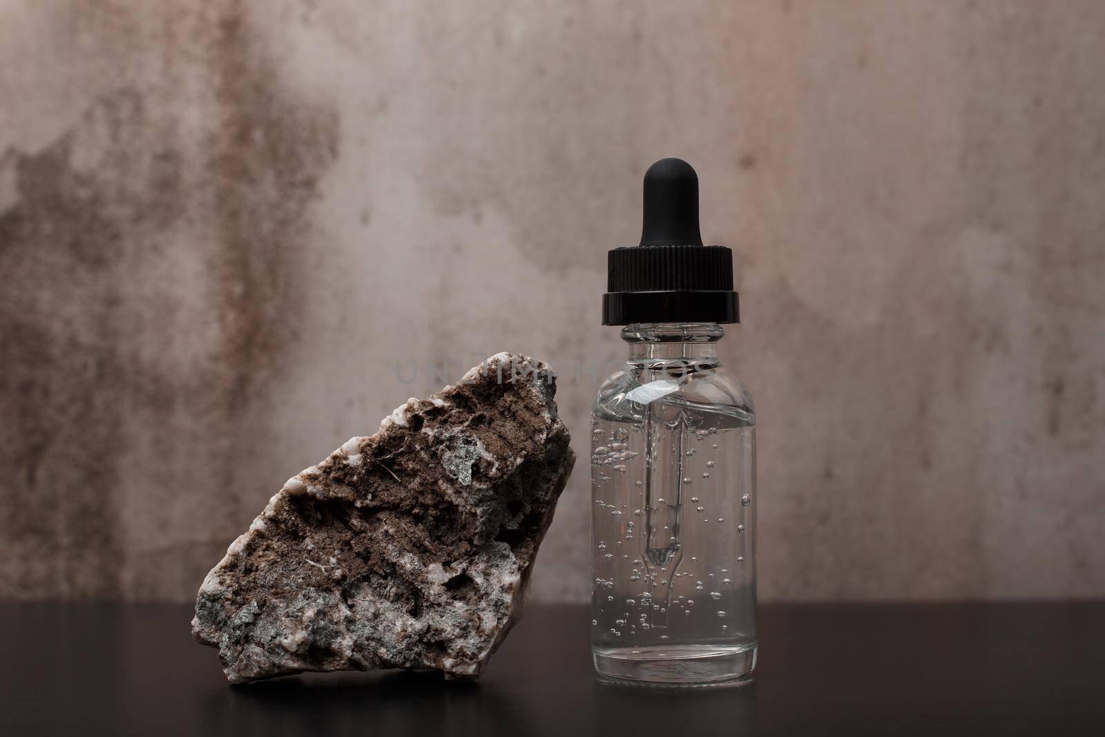 Beauty serum next to a stone on black table against dark marble background. Concept of luxury skincare  by Senorina_Irina