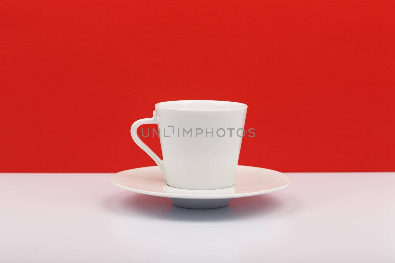 White coffee or tea cup on white table against red background by Senorina_Irina